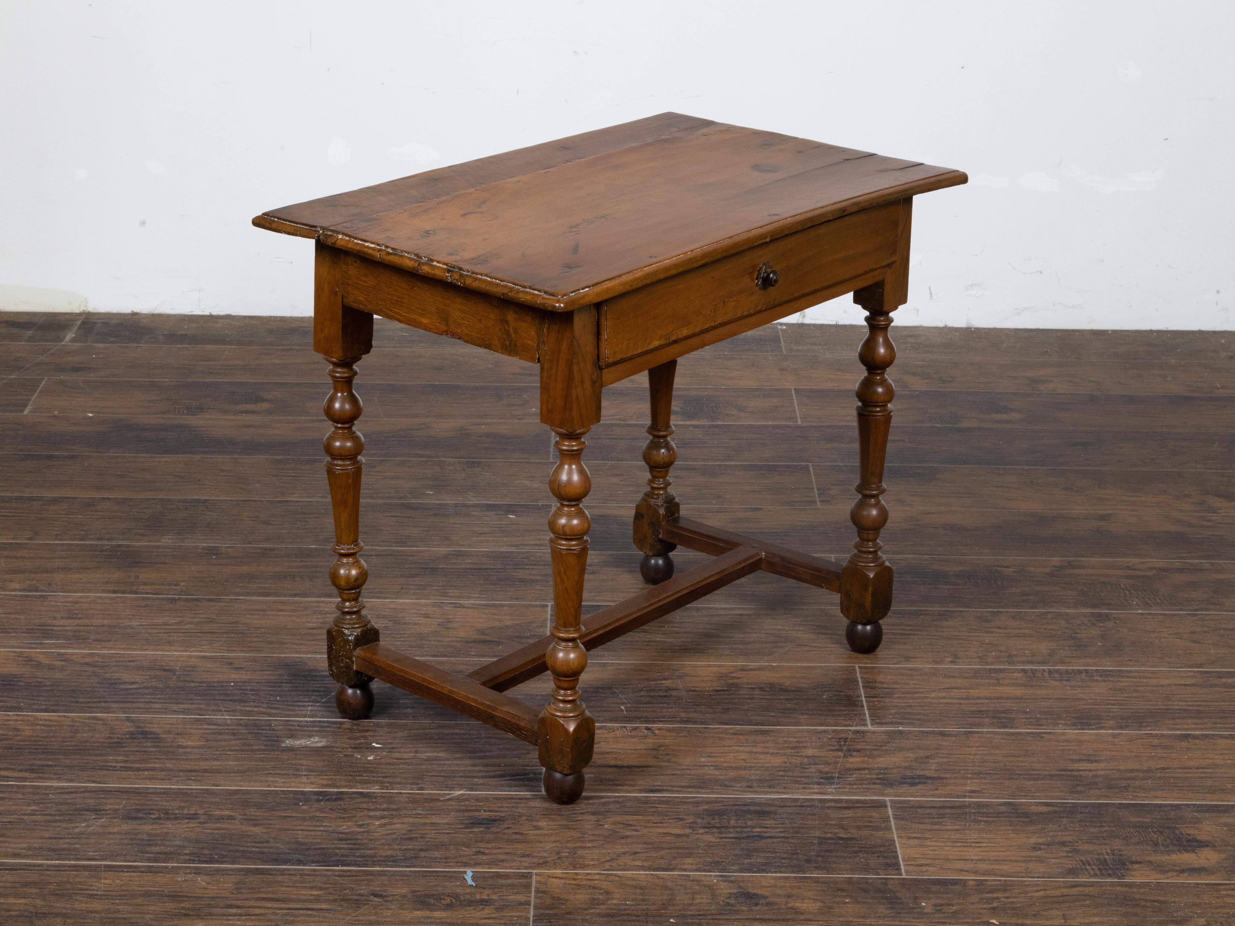 A French walnut side table from the early 19th century with rectangular top, single drawer, turned baluster legs and H-Form cross stretcher on rectangular block joints and small ball feet. This French walnut side table, hailing from the early 19th