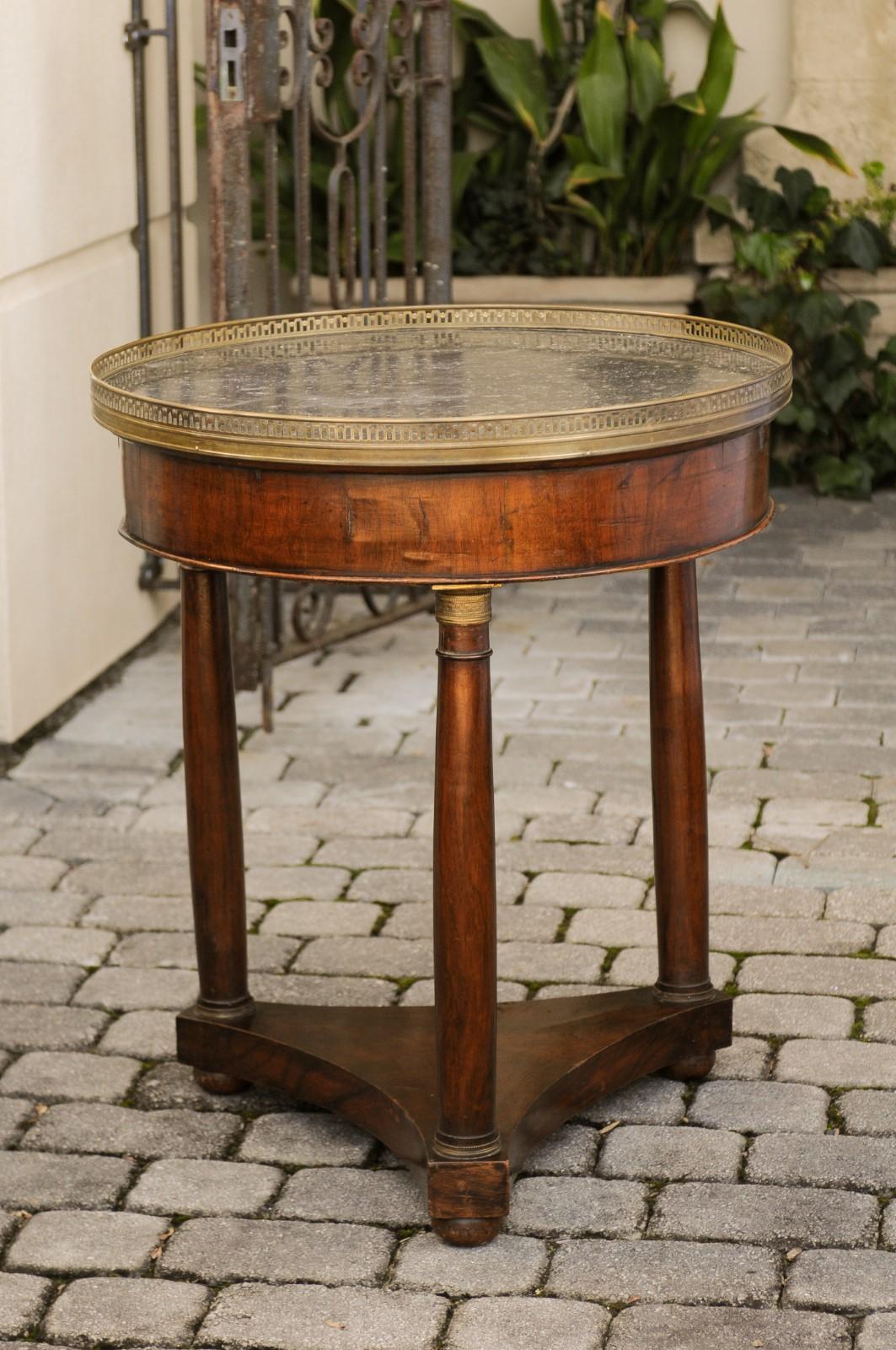 A French period Empire walnut guéridon side table from the early 19th century, with grey marble top and bronze mounts. Born in the first quarter of the 19th century under the reign of France's first Emperor Napoleon I, this exquisite guéridon
