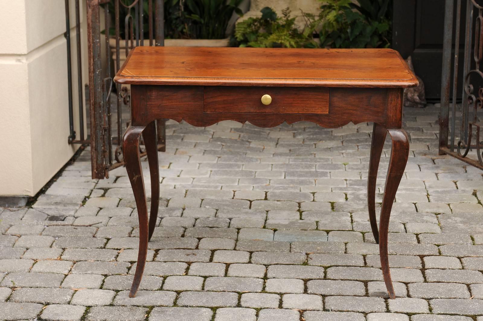 A French Louis XV style oak side table with single drawer, scalloped apron and cabriole legs from the early 19th century. Born during the early years of the 19th century, this French side table features a rectangular top with rounded corners and