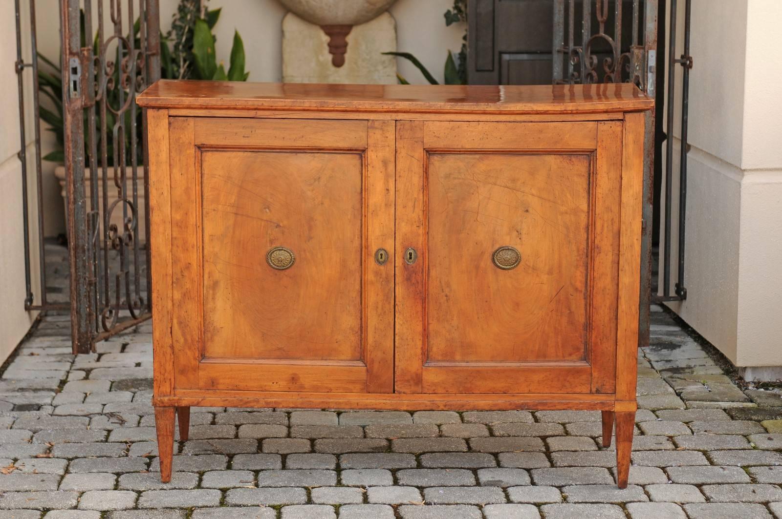 A French neoclassical period walnut two-door buffet with inner drawers and shelves from the early 19th century. Delve into the understated elegance of the early 19th century with this French neoclassical period walnut buffet, a piece that