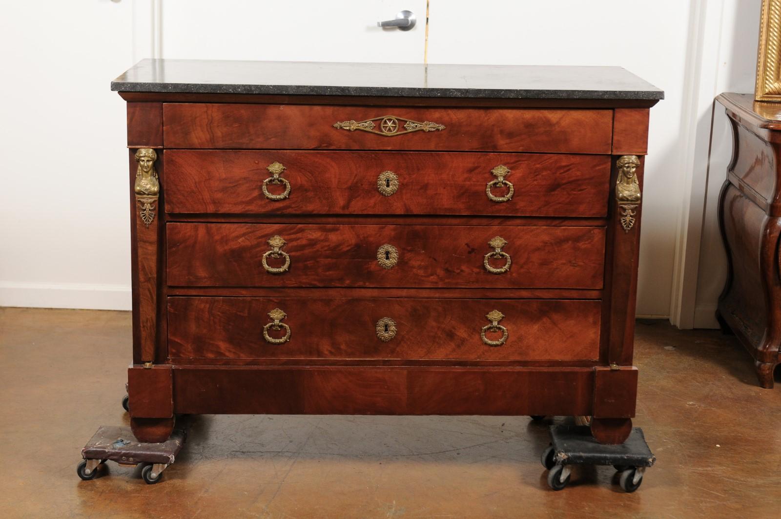 A French Empire mahogany four-drawer commode from the second quarter of the 19th century, with dark grey stone top and bronze mounts. Born at the end of the French Restauration period that saw the return of monarchy after the first Revolution, this