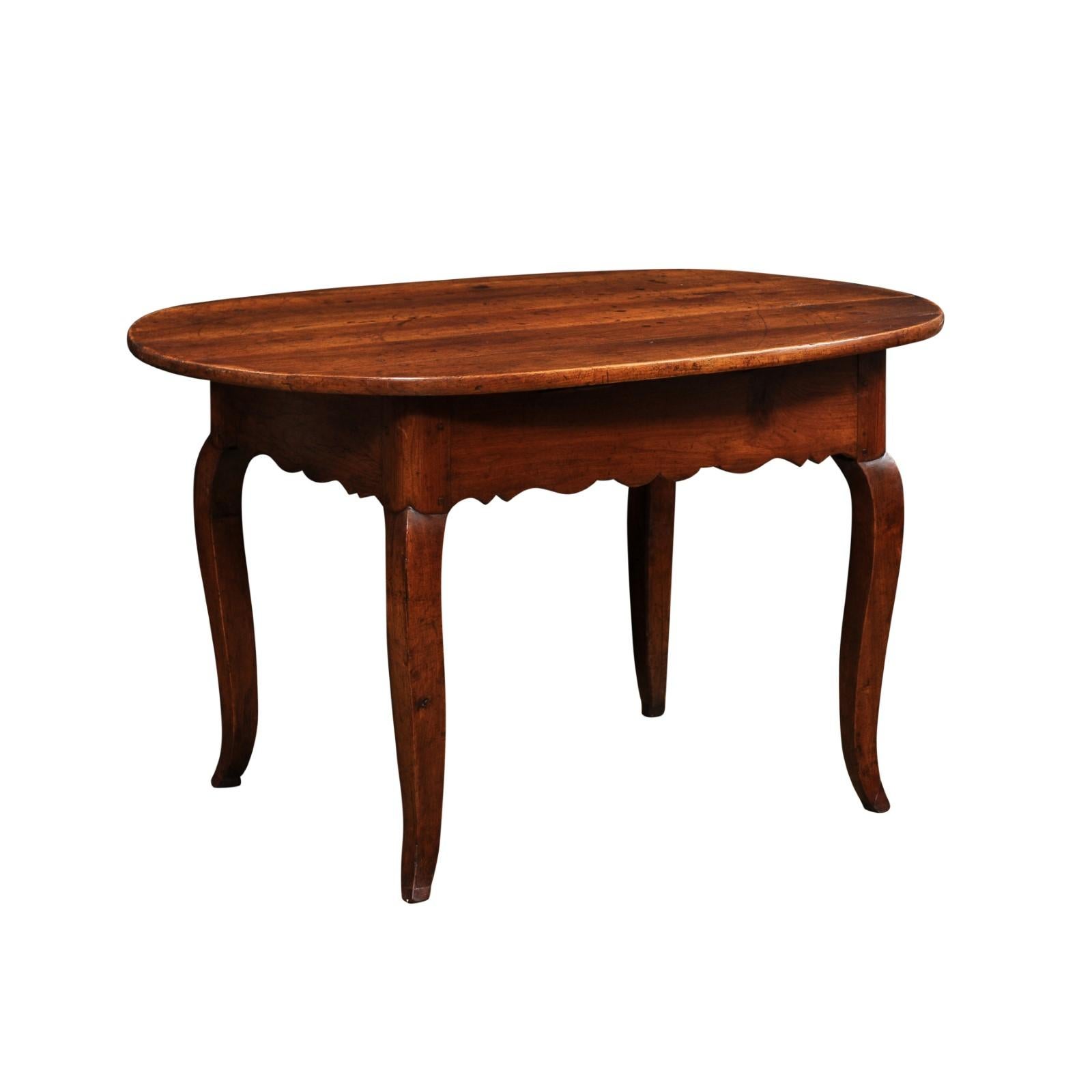 A French Louis XV style wooden center table from the early 19th century, with oval top, cabriole legs and carved apron. Created in France during the Restauration period which saw the return of the monarchy after the Revolution, this center table