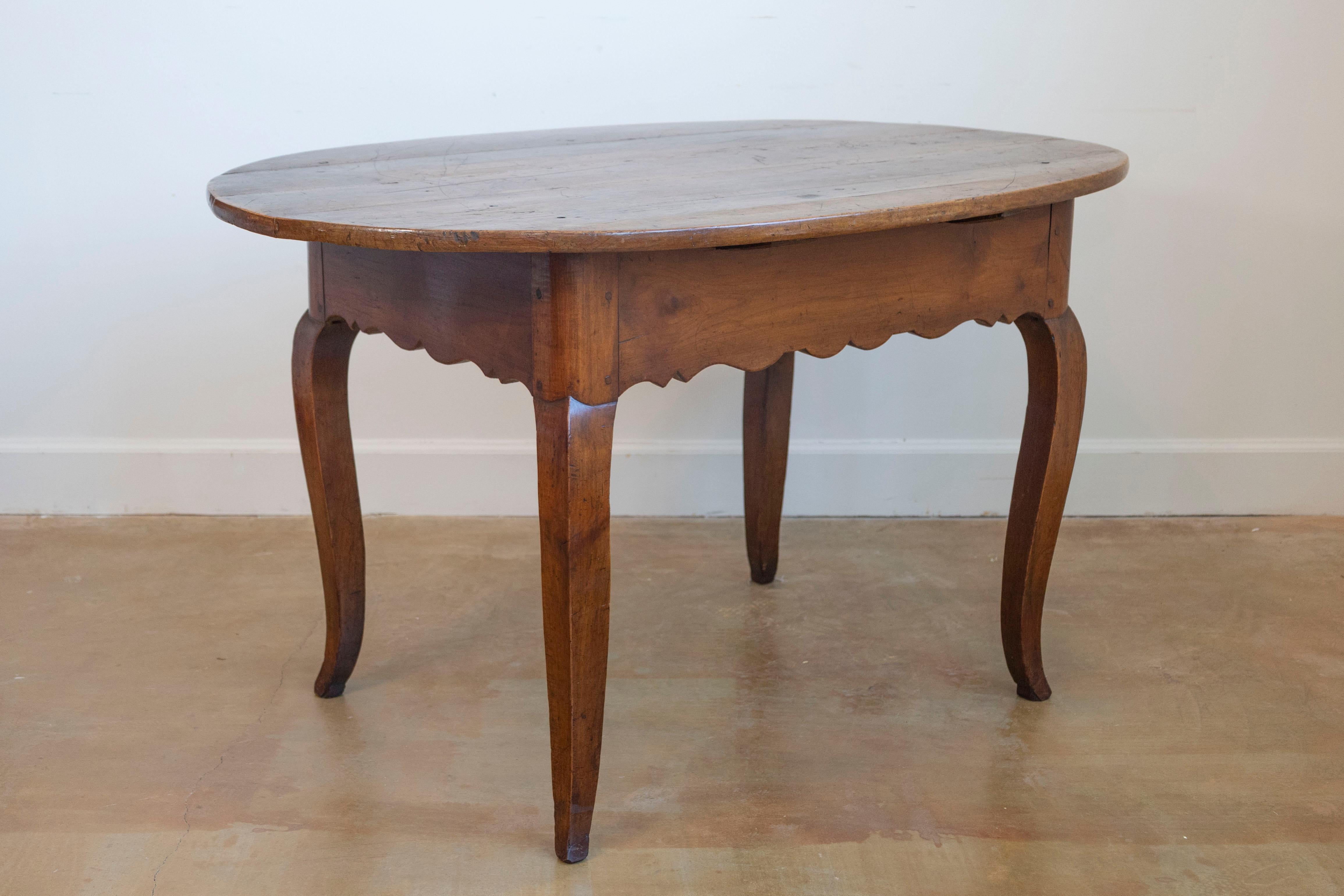 A French Louis XV style wooden center table from the early 19th century, with oval top, cabriole legs and carved apron. Created in France during the Restauration period which saw the return of the monarchy after the Revolution, this center table