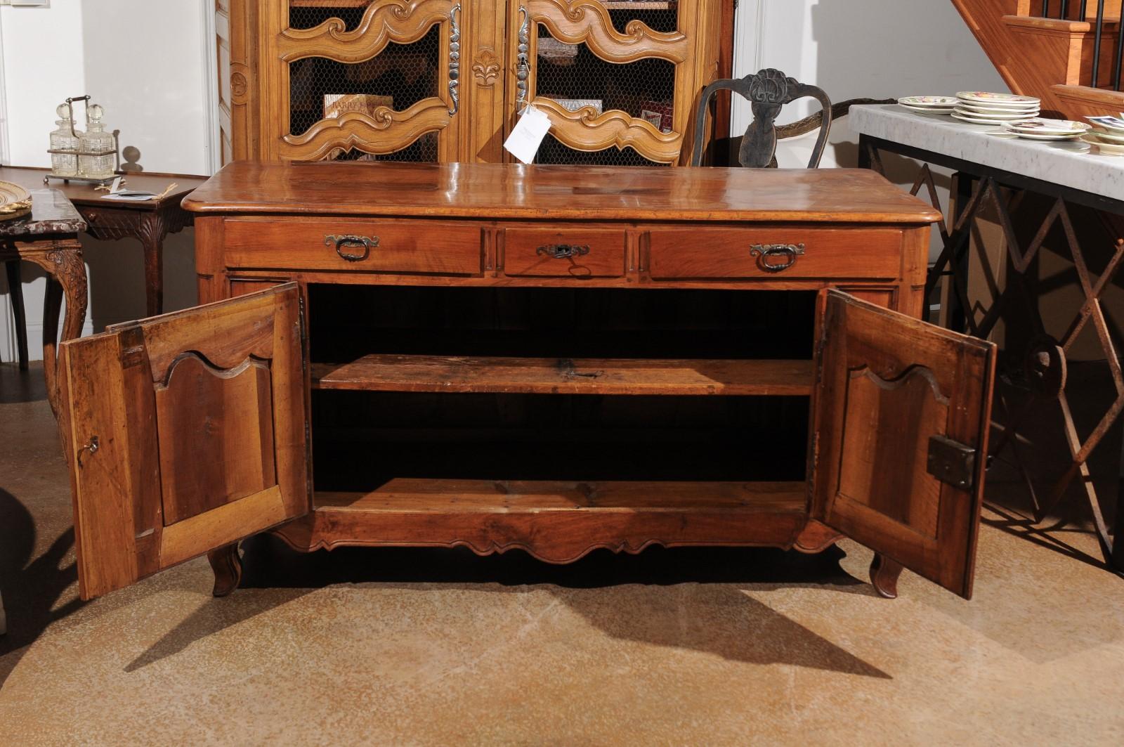 A French Louis XV style double faced walnut buffet from the second quarter of the 19th century, with three drawers and two doors. Born during the reign of France's last king Louis-Philippe, this walnut buffet features a rectangular top with beveled