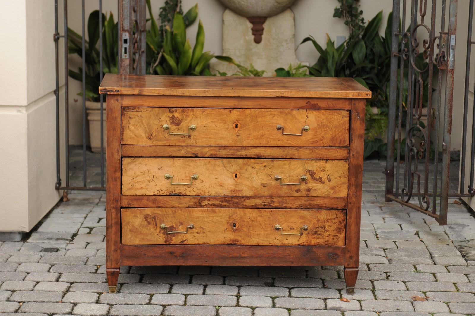 A French neoclassical style burl elm wood commode from the second quarter of the 19th century, with three drawers and short tapered feet. Born under the reign of the last King of France Louis-Philippe, this French commode features a rectangular
