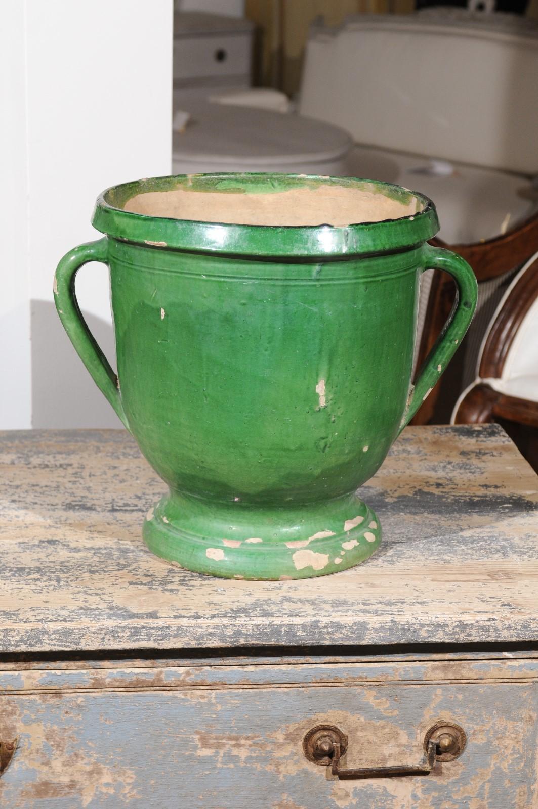 A French green glazed pottery jardinière from the mid-19th century, with lateral handles. Born in France during the reign of emperor Napoleon III, this charming jardinière planter features a green glazed body presenting a nicely weathered