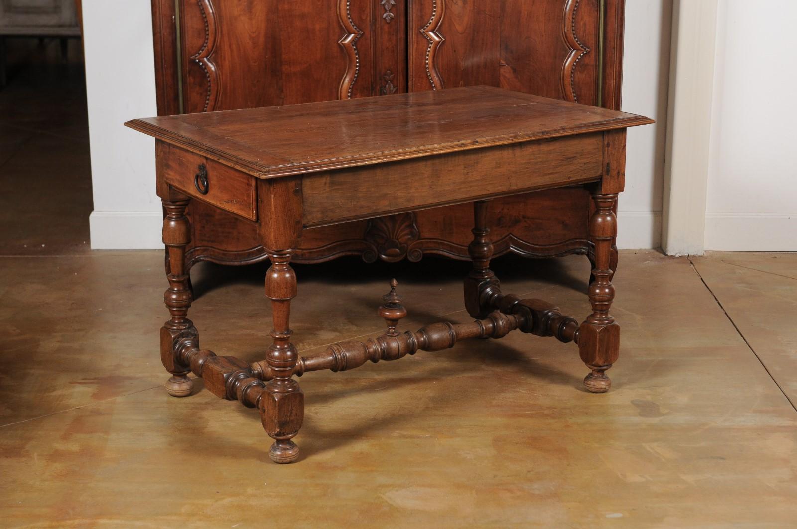 A French Louis XIII style cherry table from the mid-19th century with lateral drawer, turned legs and carved finial. Created in France at the beginning of the reign of Napoleon III's reign, this cherry table showcases the stylistic characteristics