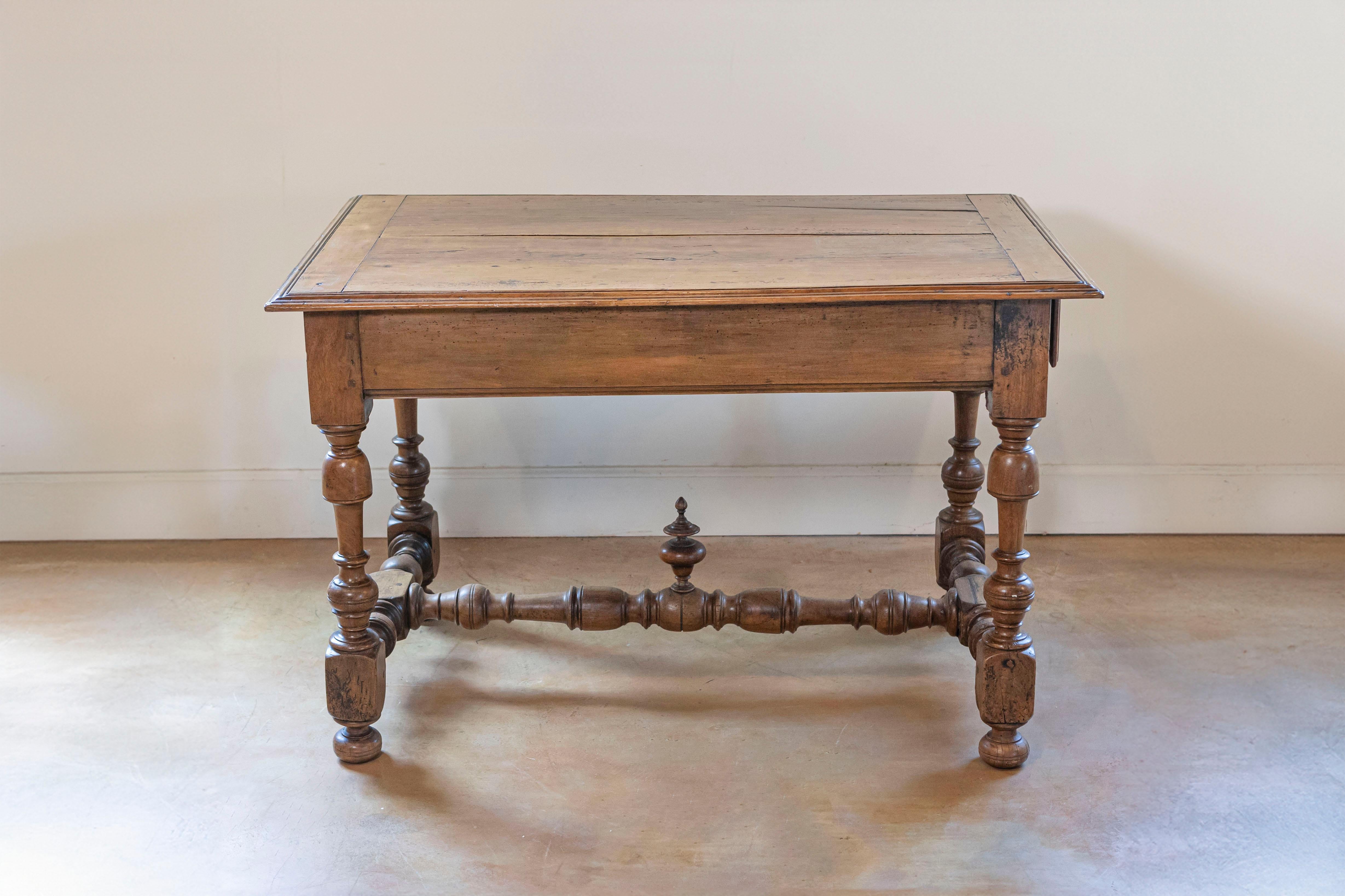 Mesa francesa de cerezo estilo Luis XIII de mediados del siglo XIX con cajón lateral, patas torneadas y remate tallado. Creada en Francia a principios del reinado de Napoleón III, esta mesa de cerezo presenta las características estilísticas de la