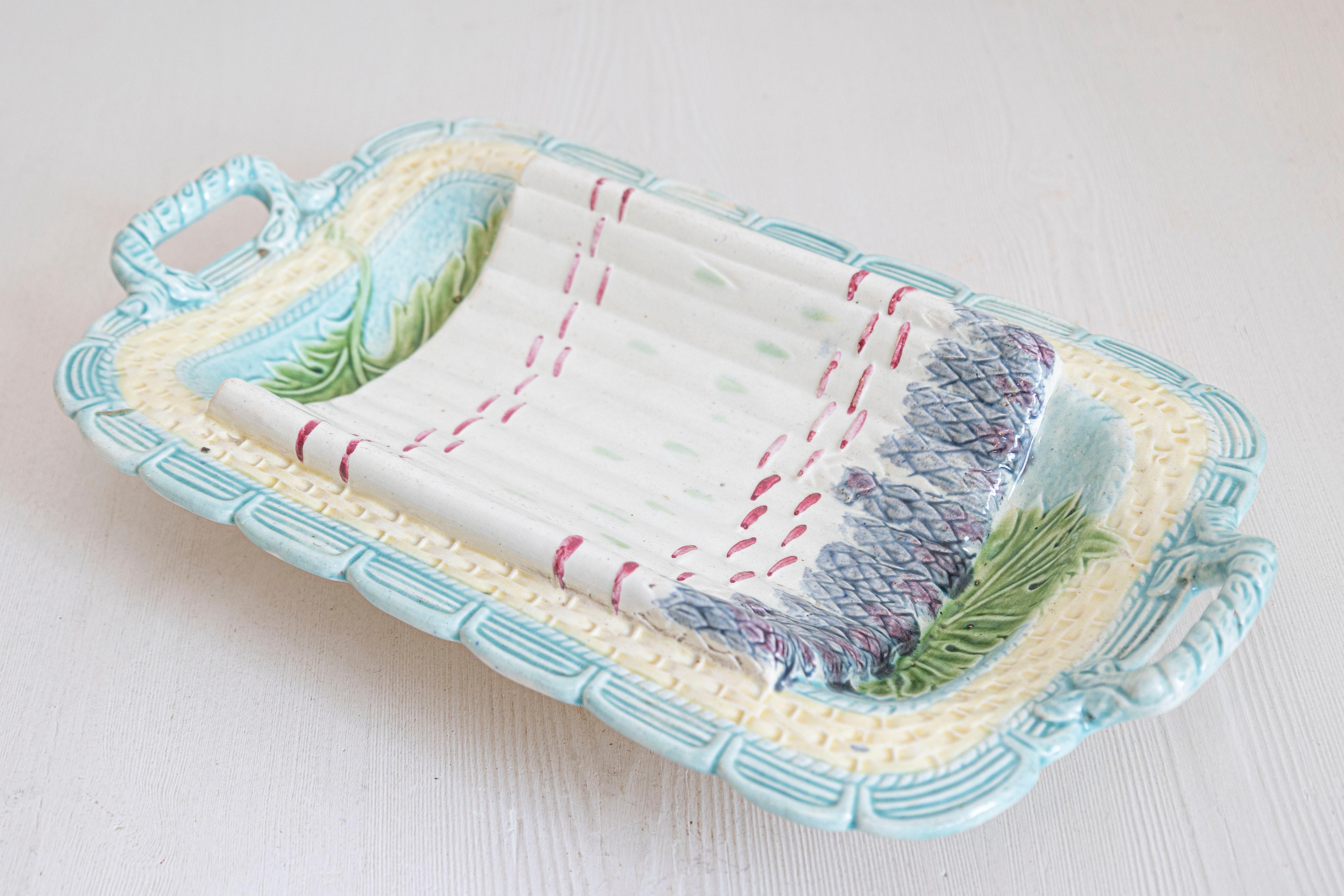Un plat de service à asperges en majolique française du milieu du 19e siècle avec des accents turquoise, violets, verts et jaunes. Créé en France dans les années 1850, ce plat en majolique présente un corps incurvé orné d'asperges violettes, roses