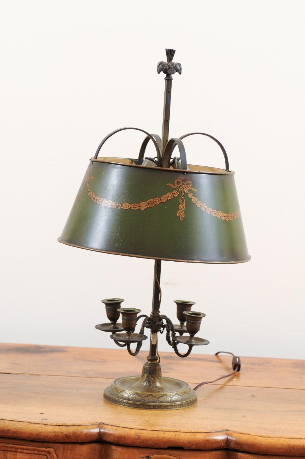 A French Napoléon III period green painted tôle table lamp from the mid-19th century, with two lights, bobèches and garlands. Created in France at the beginning of emperor Napoléon III's reign, this table lamp features a green painted tôle shade