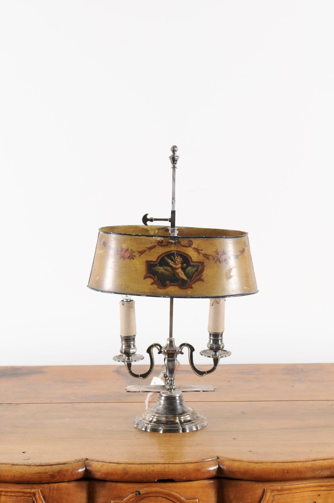 A French Napoléon III period painted tôle two-light table lamp from the mid 19th century, with cherub and rose motifs. Created in France at the beginning of Emperor Napoléon III's reign, this lamp features an oval painted tôle shade adorned with