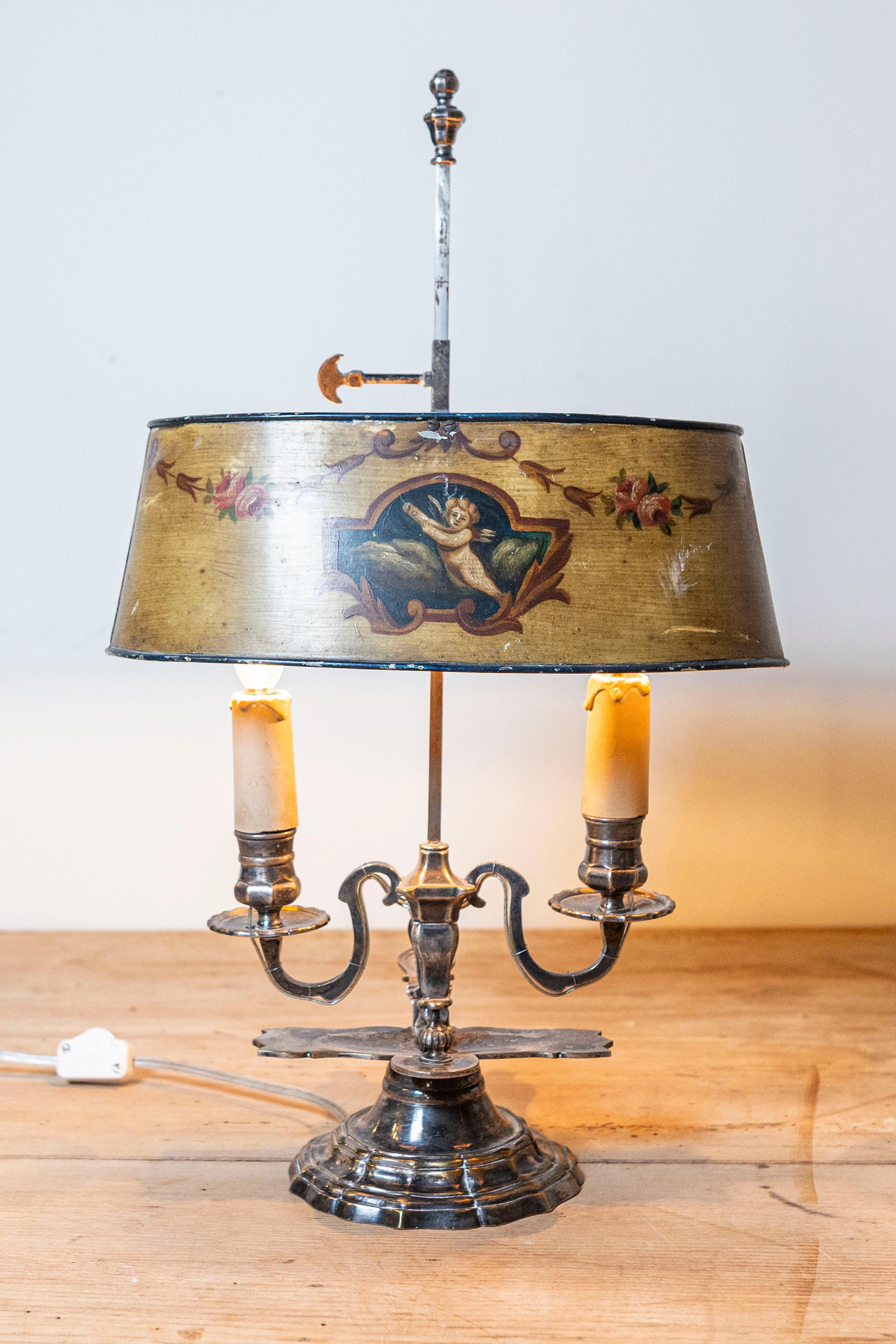 A French Napoléon III period painted tôle two-light table lamp from the mid 19th century, with cherub and rose motifs. Created in France at the beginning of Emperor Napoléon III's reign, this lamp features an oval painted tôle shade adorned with