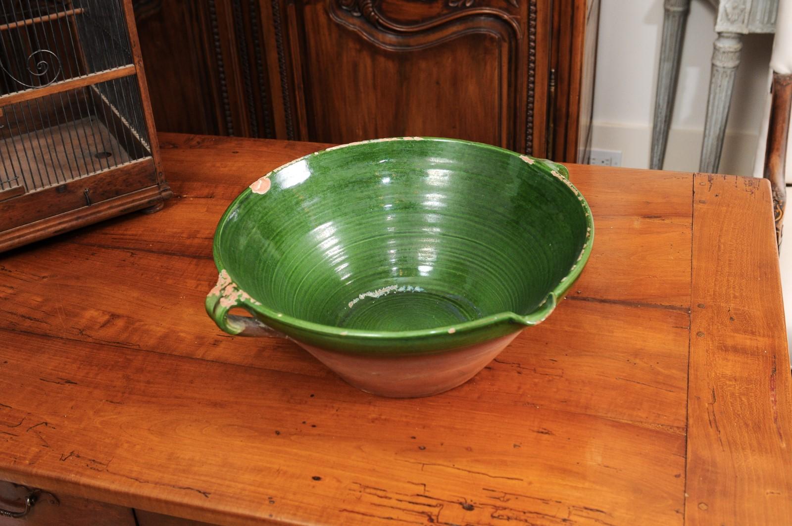 A French Provincial Napoléon III period green glazed terracotta bowl from the mid-19th century, with two handles and pouring lip. Created in France at the beginning of Emperor Napoléon III's reign, this pottery bowl features a circular body,