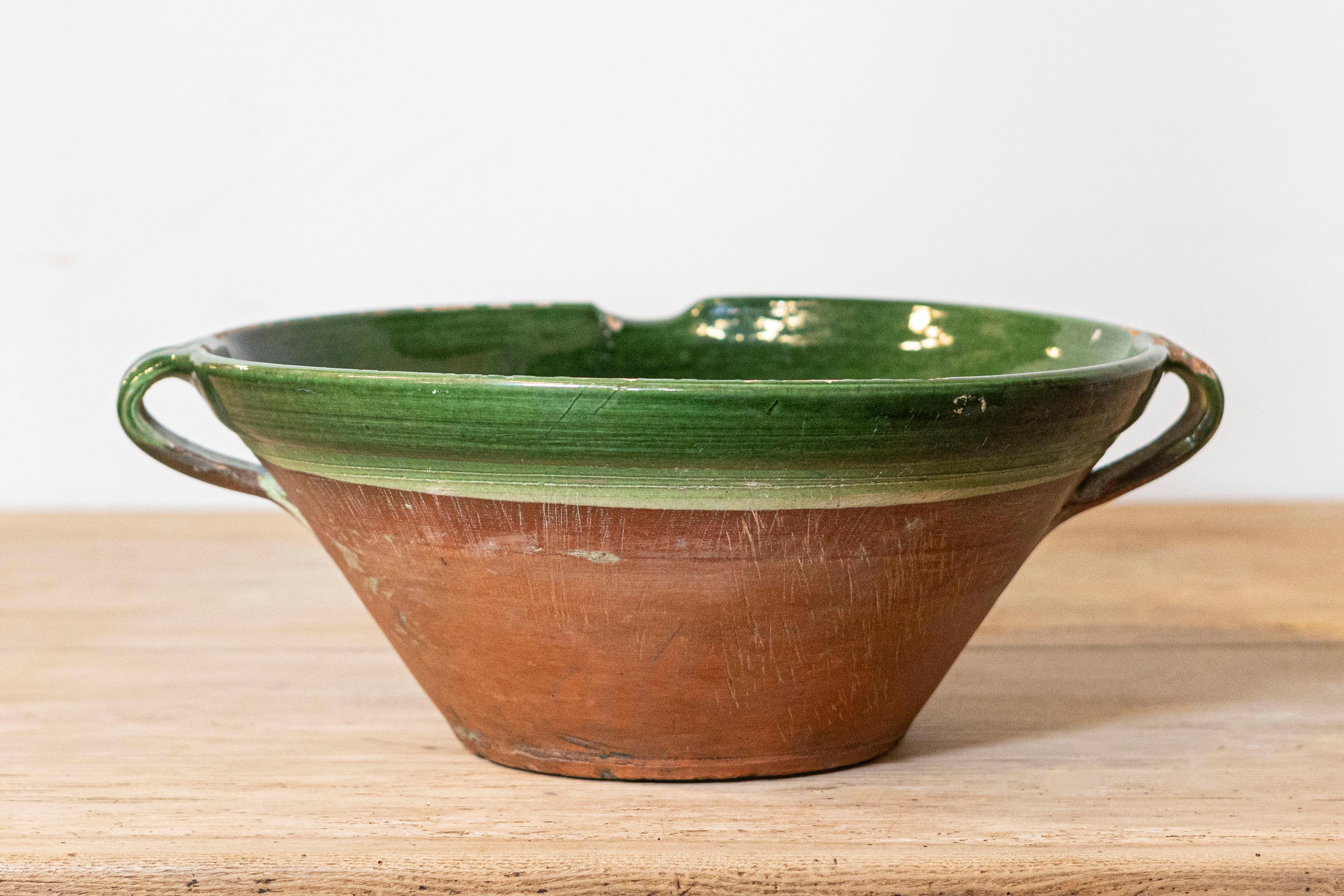 A French Provincial Napoléon III period green glazed terracotta bowl from the mid-19th century, with two handles and pouring lip. Created in France at the beginning of Emperor Napoléon III's reign, this pottery bowl features a circular body,