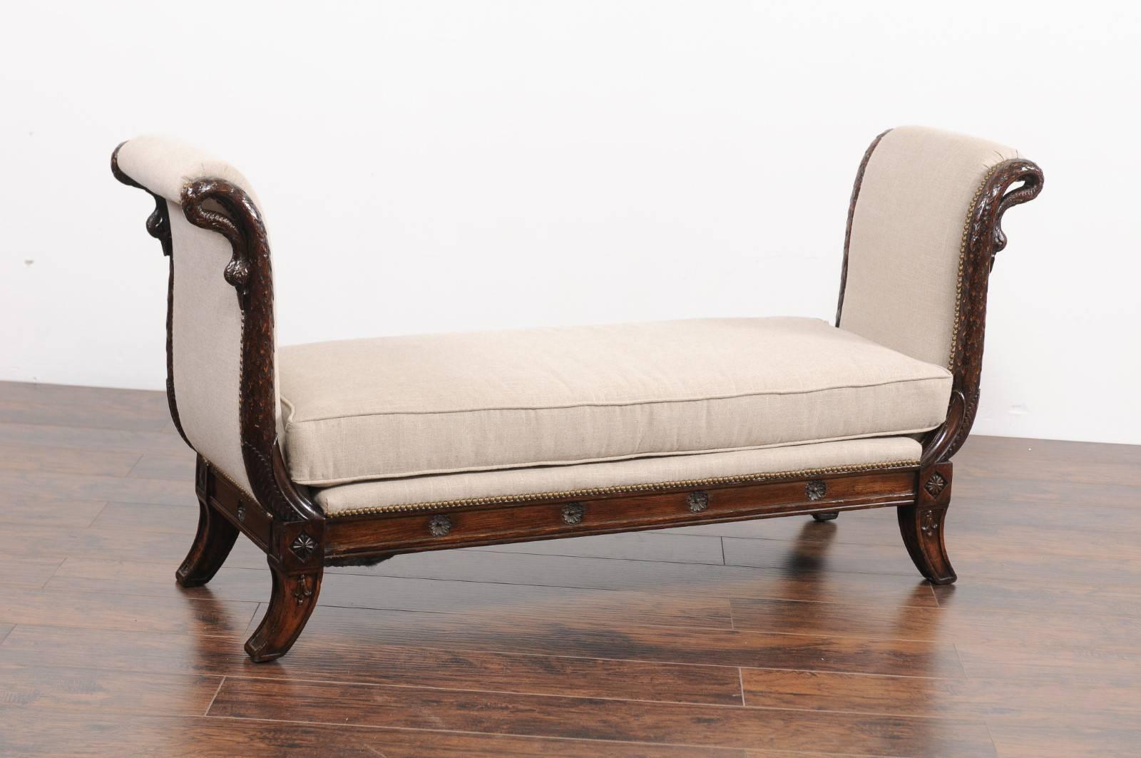 A French Empire style walnut bench from the mid-19th century, with carved swan heads and new upholstery. This French walnut backless bench features an exquisite silhouette, flanked without-scrolled sides adorned with delicate carved swan figures.