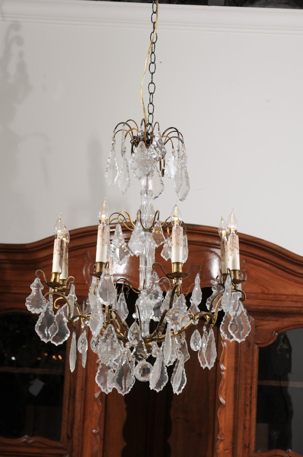 A French Napoleon III period eight-light crystal chandelier from the mid-19th century with brass armature. Born in France during the reign of Emperor Napoleon III's reign, this exquisite chandelier features a crystal shaft topped with scrolling