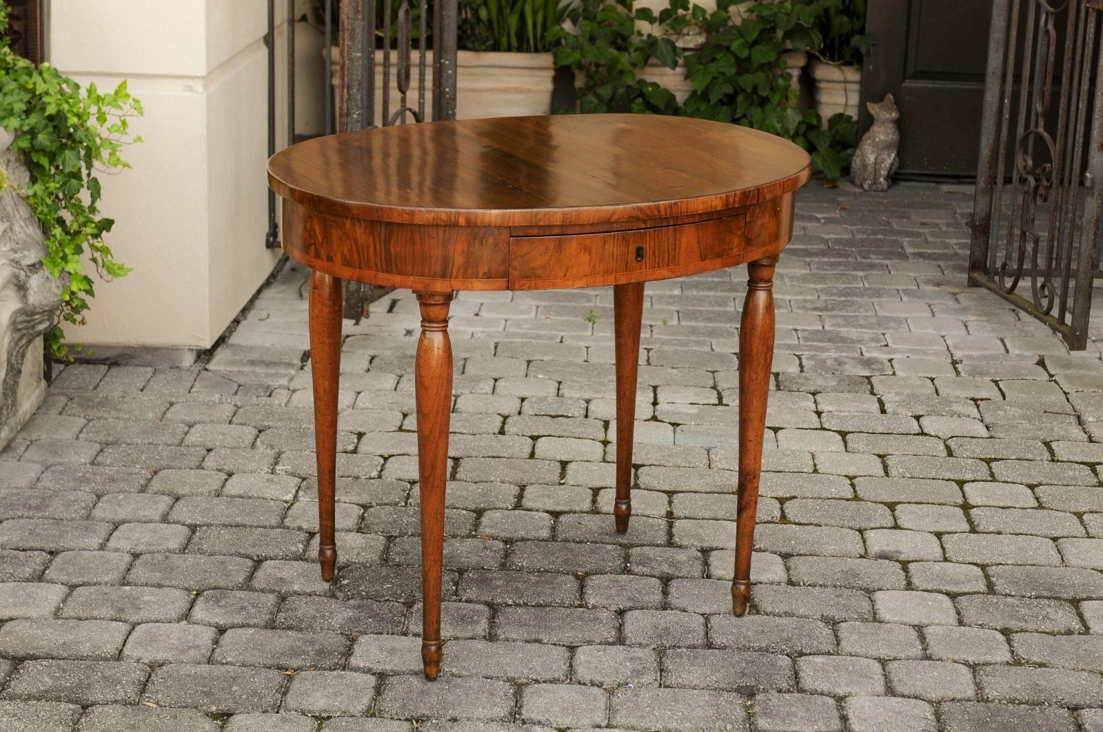 A French Napoleon III period oval walnut table from the mid-19th century, with single drawer and cylindrical tapering legs. Born in France during the second half of the 19th century, this elegant table features an oval top, sitting above an apron