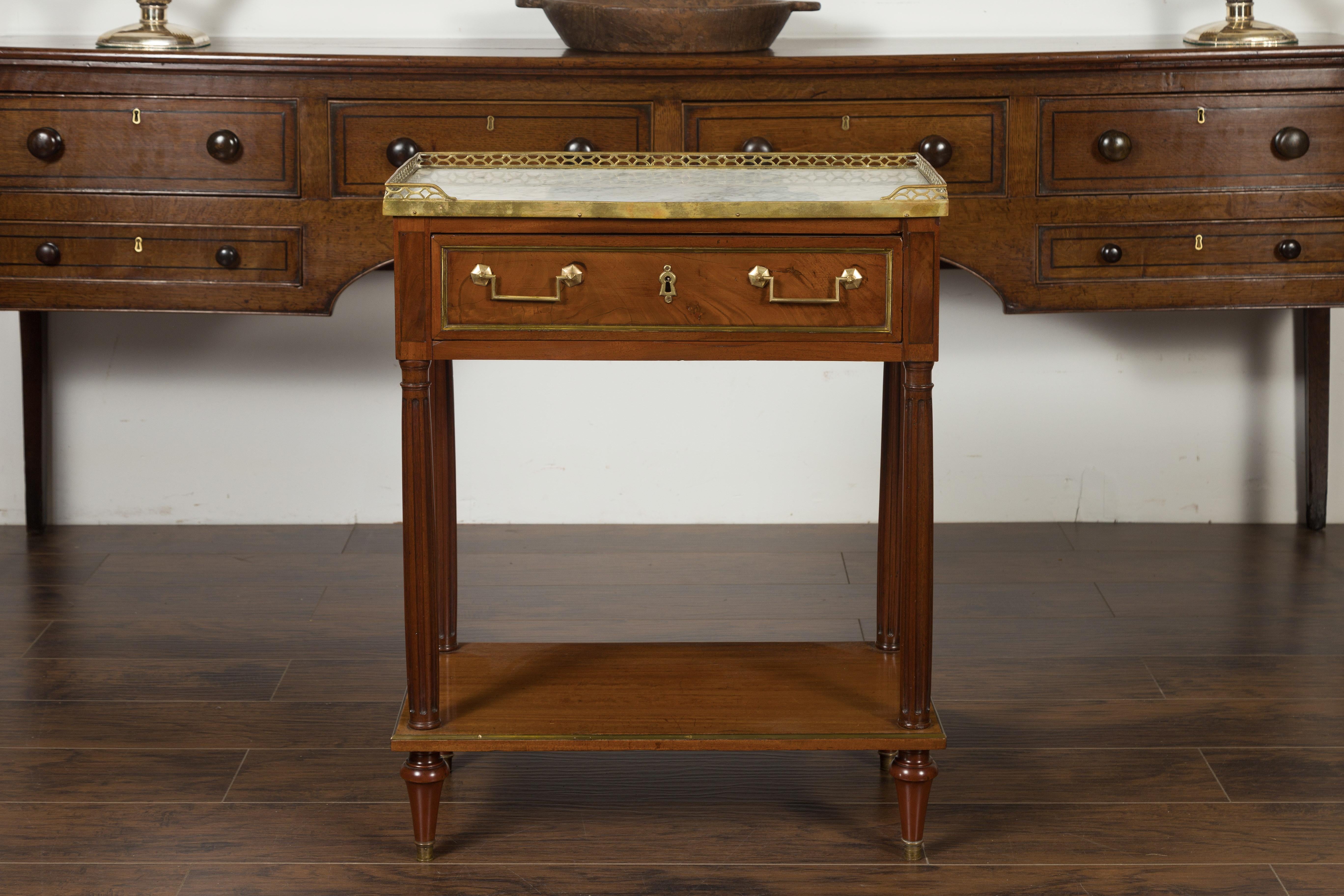 A French Napoleon III period mahogany console table from the mid-19th century, with marble top, brass accents and fluted columns. Born during the reign of France's last emperor Napoleon III, this console table features a white veined marble top