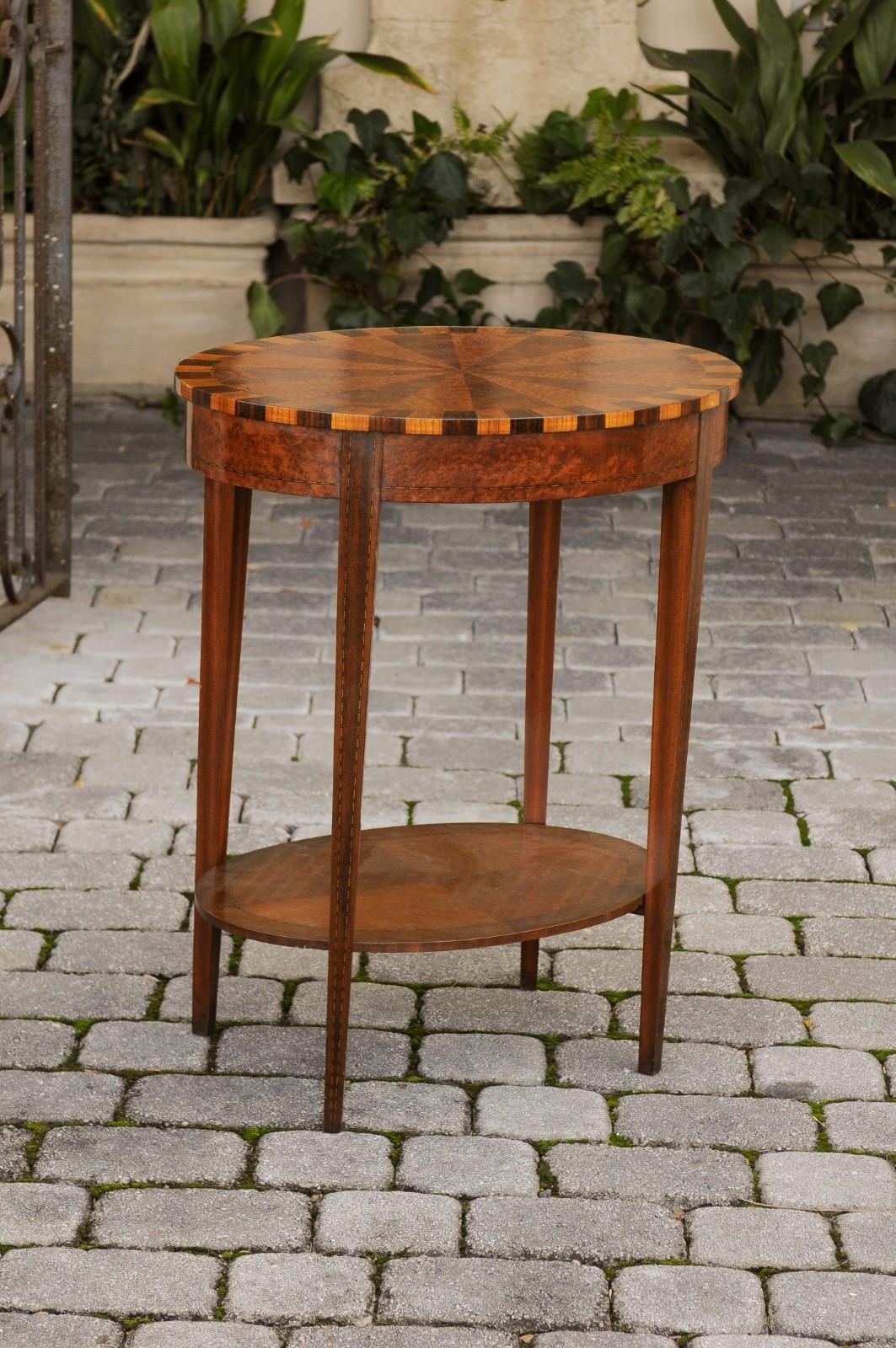 A French oval walnut side table from the mid-19th century, with radiating inlaid top and lower shelf. Born during the reign of France's last Emperor Napoleon III, this side table features an exquisite oval top, adorned with radiating motifs