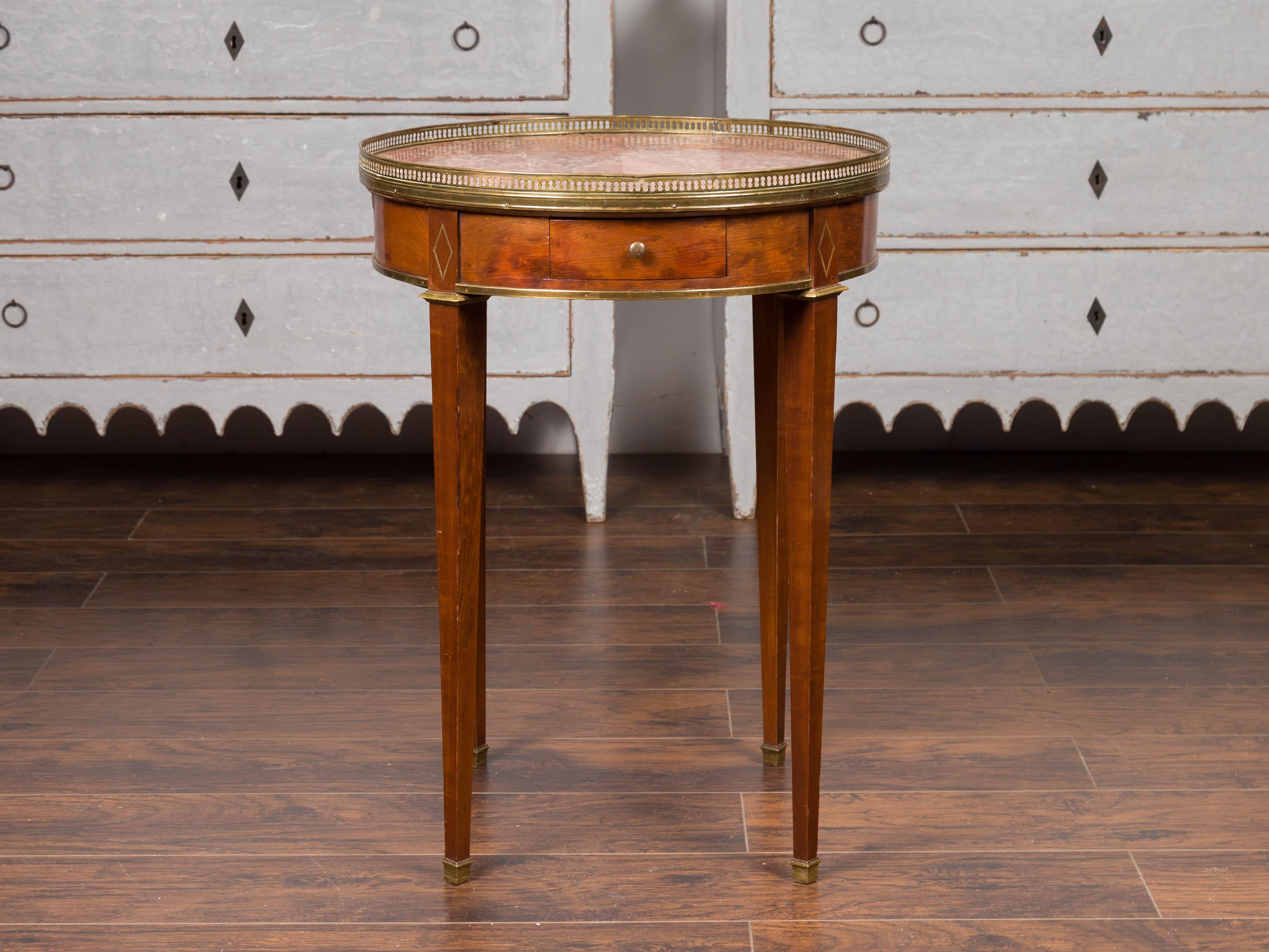 A French Empire style round side table from the late 19th century, with red marble top, single drawer and brass accents. Born in France during the third quarter of the 19th century, this side table features a circular red marble top surrounded by a