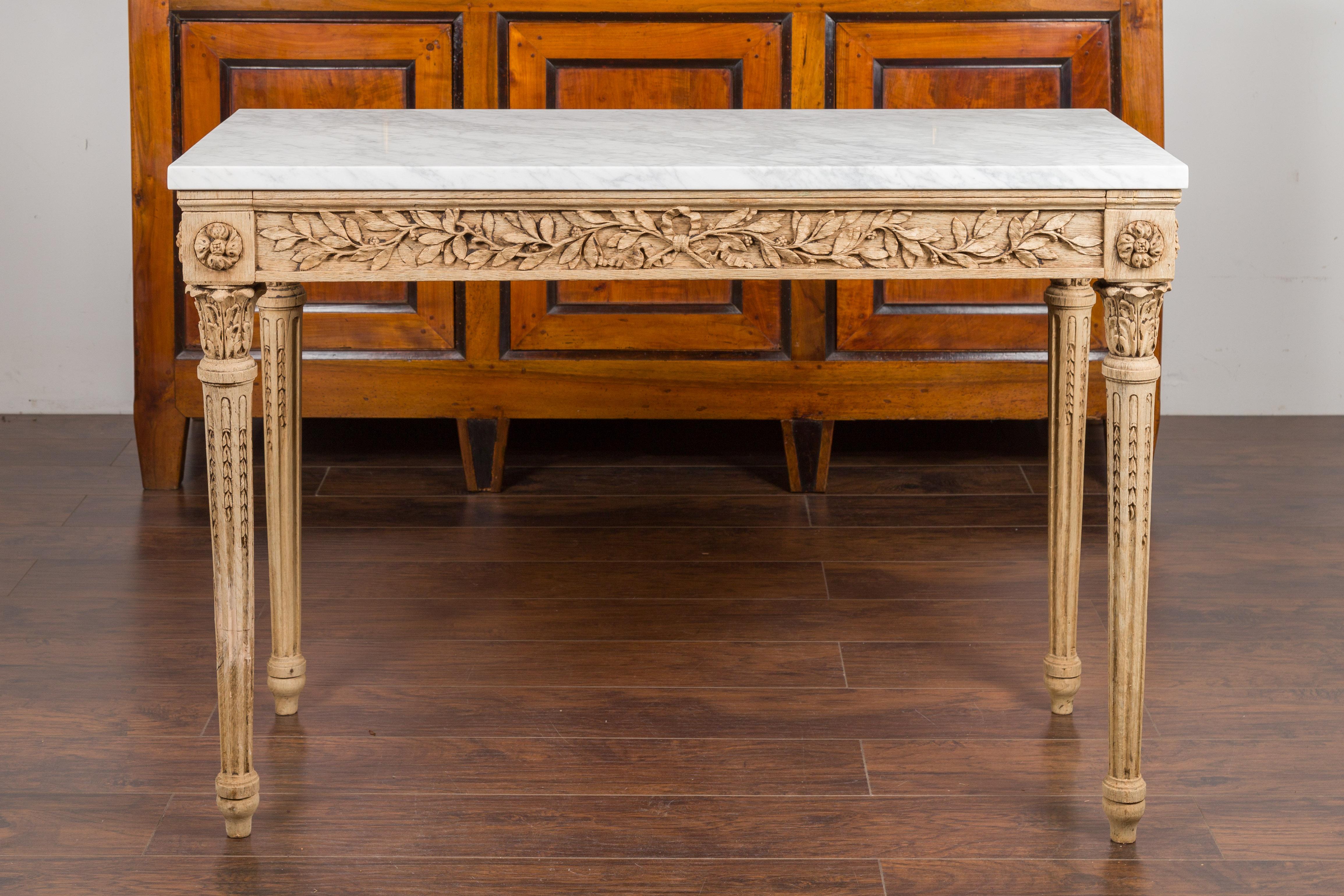 A French Napoléon III period carved and bleached console table from the late 19th century, with white marble top. Created in France at the end of Emperor Napoléon III's reign, this console table captures our attention with its richly carved décor