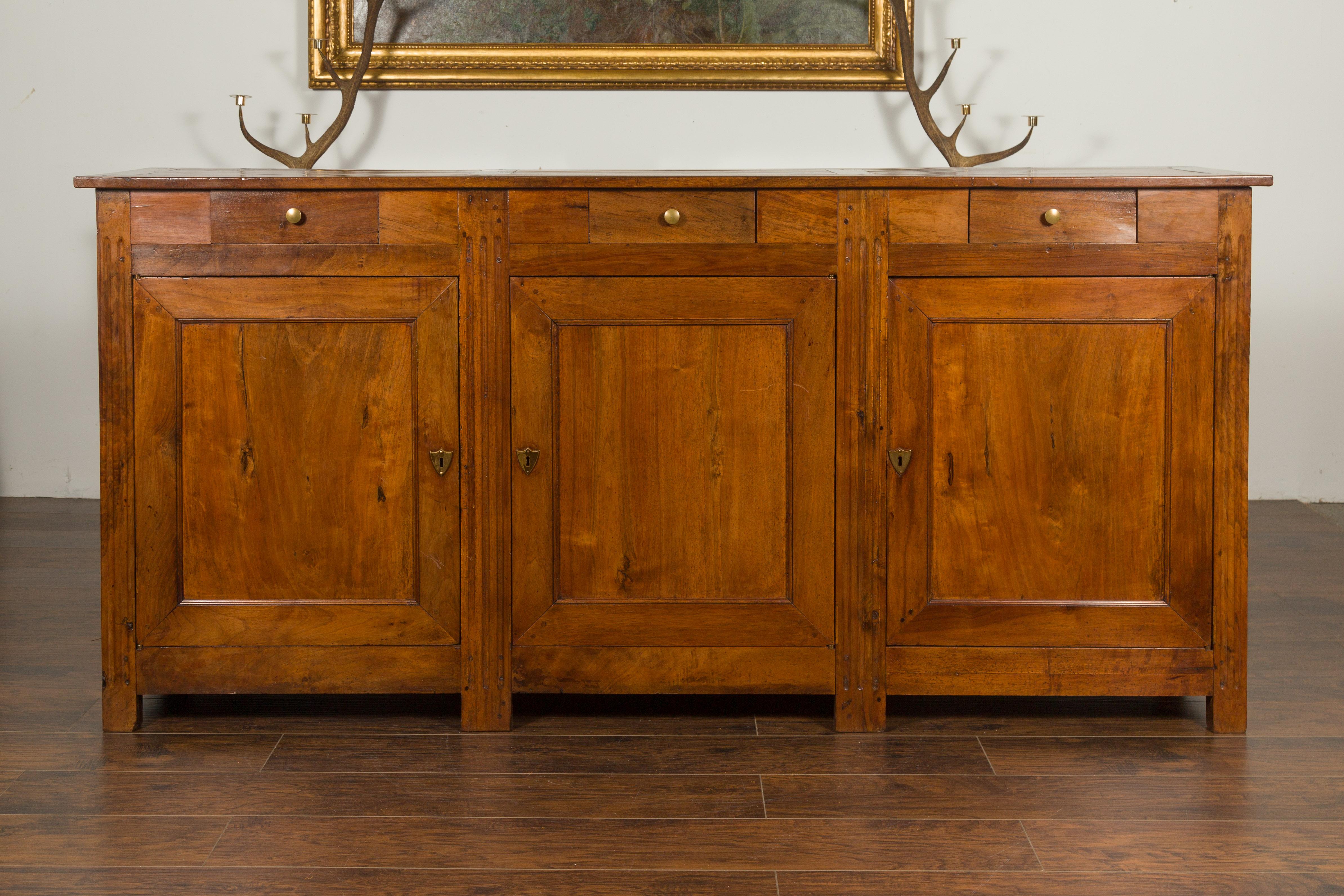 A French Napoleon III period walnut enfilade from the late 19th century, with three drawers over three doors. Created at the end of France's last emperor's reign, this walnut enfilade features a rectangular top divided into three sections, sitting