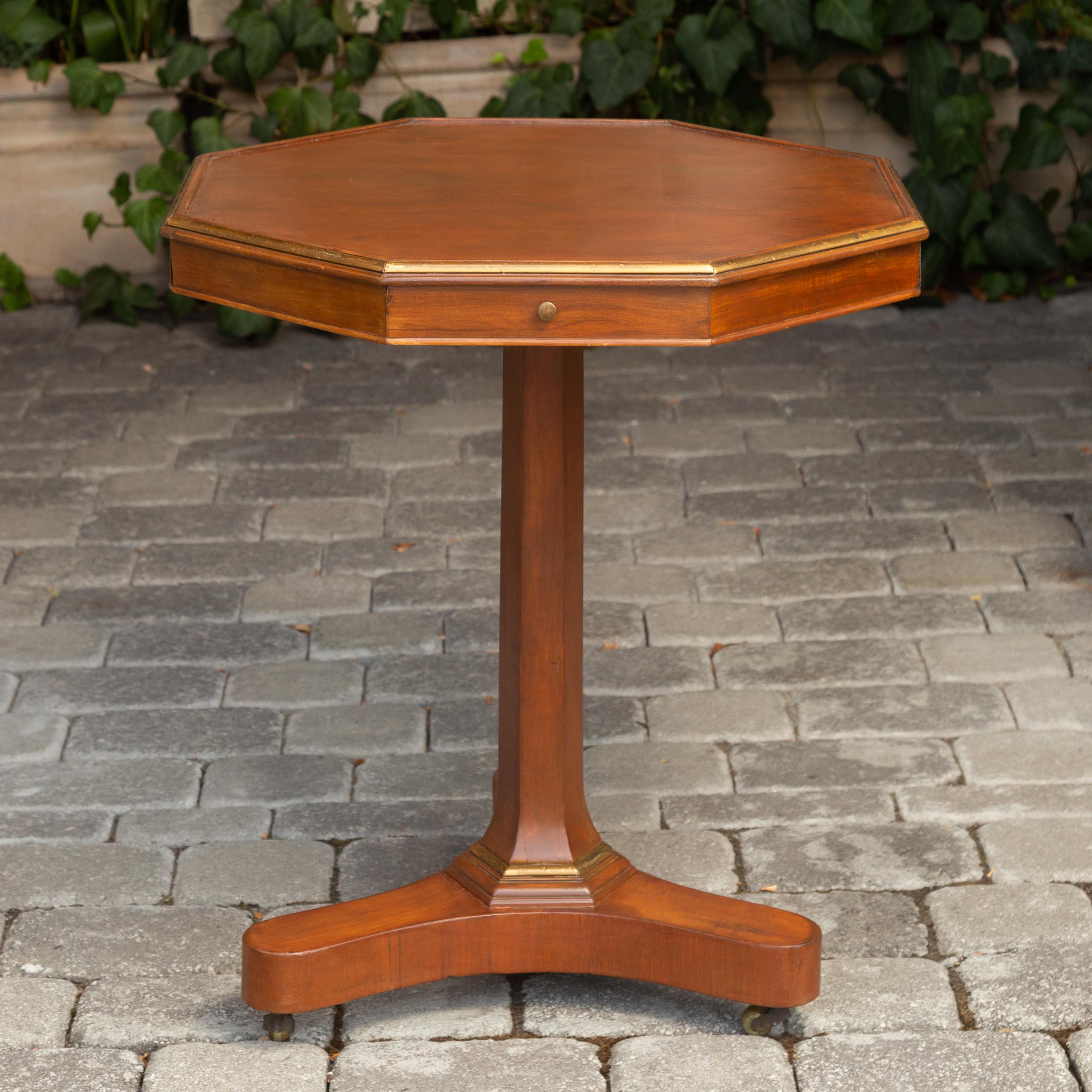 A French walnut octagonal guéridon table from the late 19th century, with copper trim, four drawers and pedestal base. Born in France at the end of the reign of Emperor Napoleon III, this exquisite guéridon table features an octagonal top surrounded