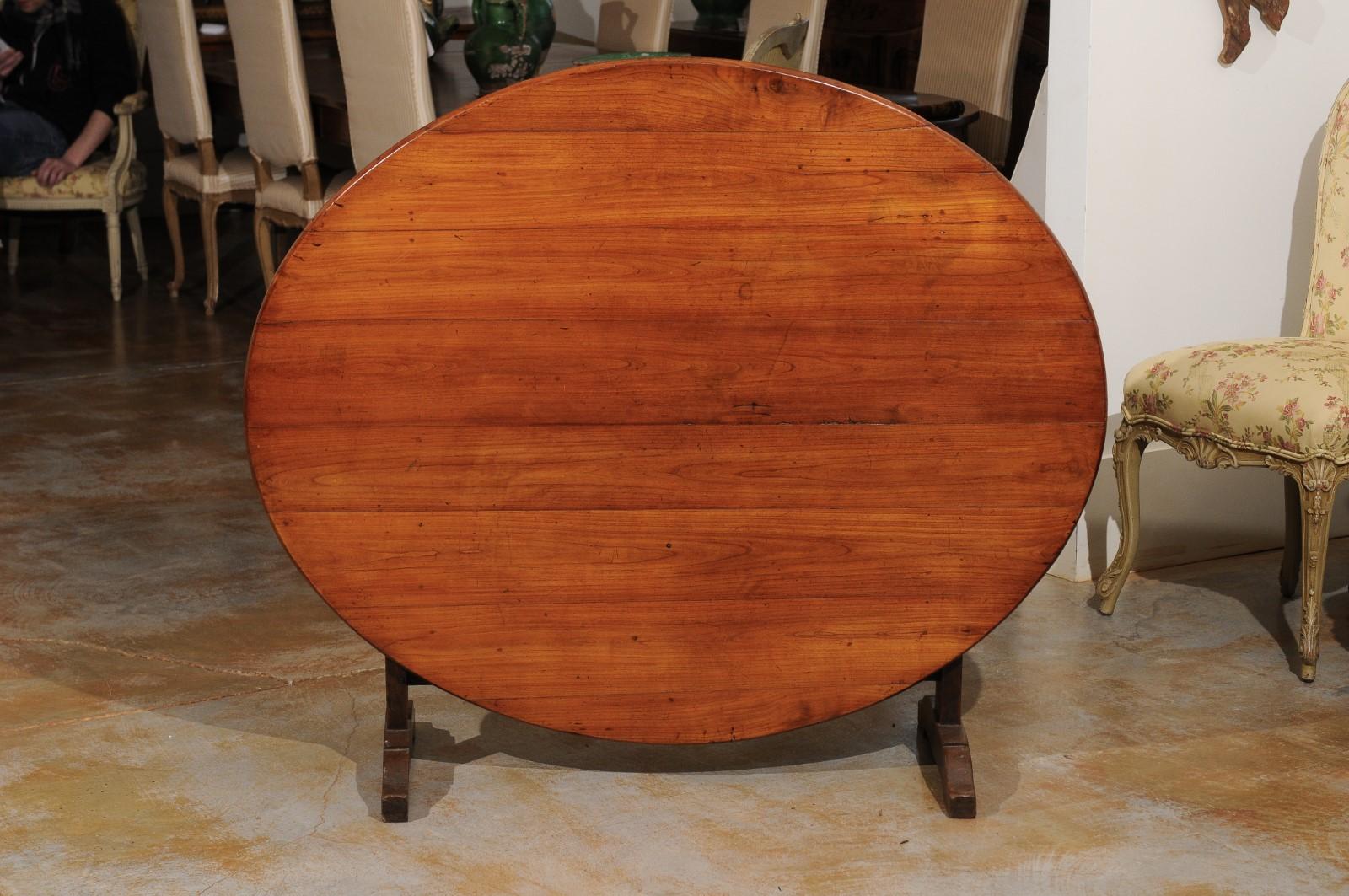 A French oval wine tasting table from the late 19th century, with tilt-top and butterfly wedge. Born in France at the end of the reign of France's last Emperor Napoleon III, this wine tasting table features an oval tilt-top, sitting above a trestle