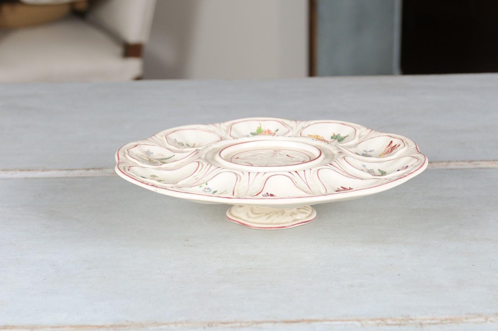 A French Longchamp majolica oyster platter from the late 19th century, with flowers and petite base. Created in France during the last quarter of the 19th century, this Majolica oyster platter is adorned with delicate flowers boasting pink, purple