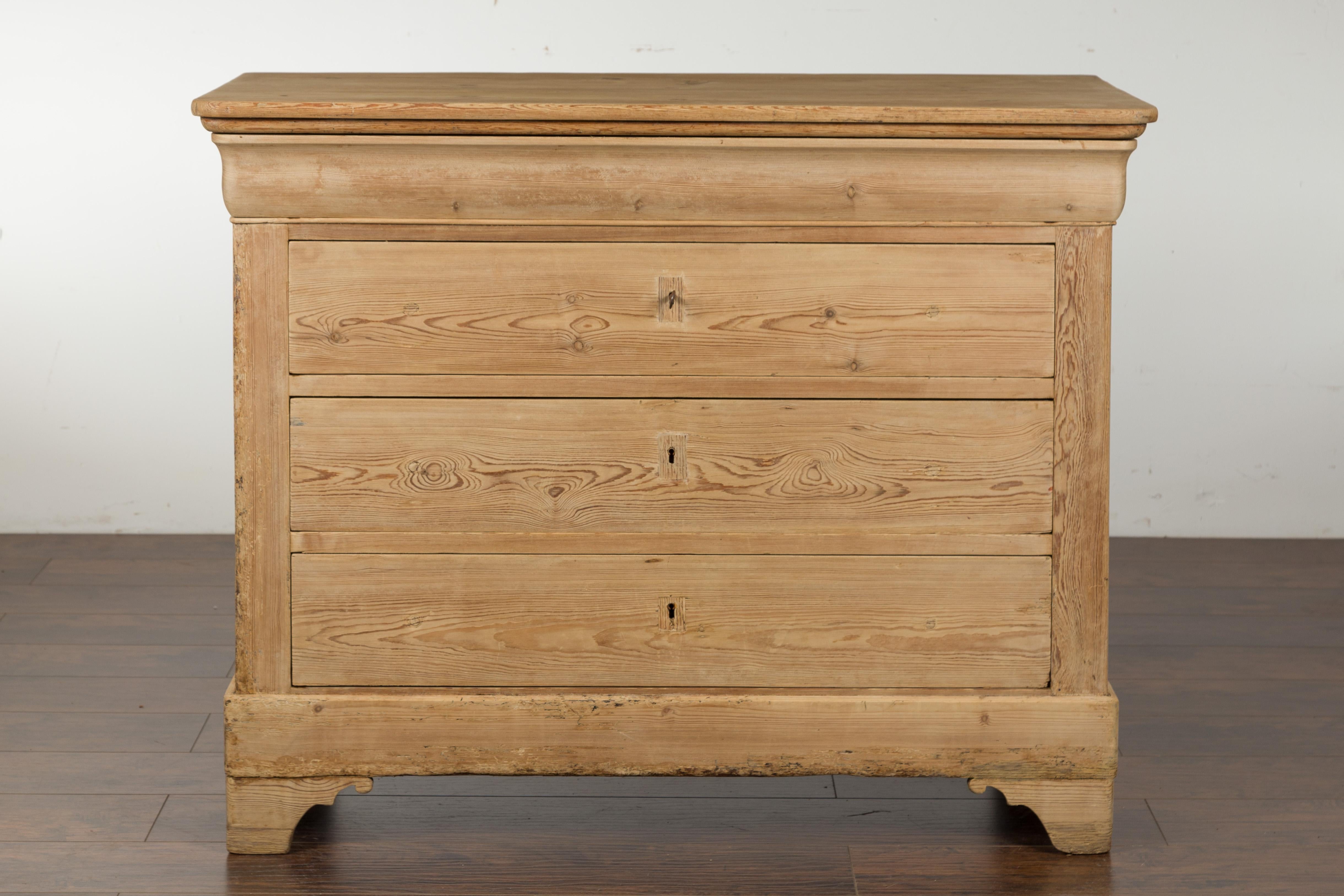 A French Louis-Philippe style four-drawer pine commode from the late 19th century, with bracket feet. Created in France during the last quarter of the 19th century, this pine commode features a rectangular top with rounded corners in the front,