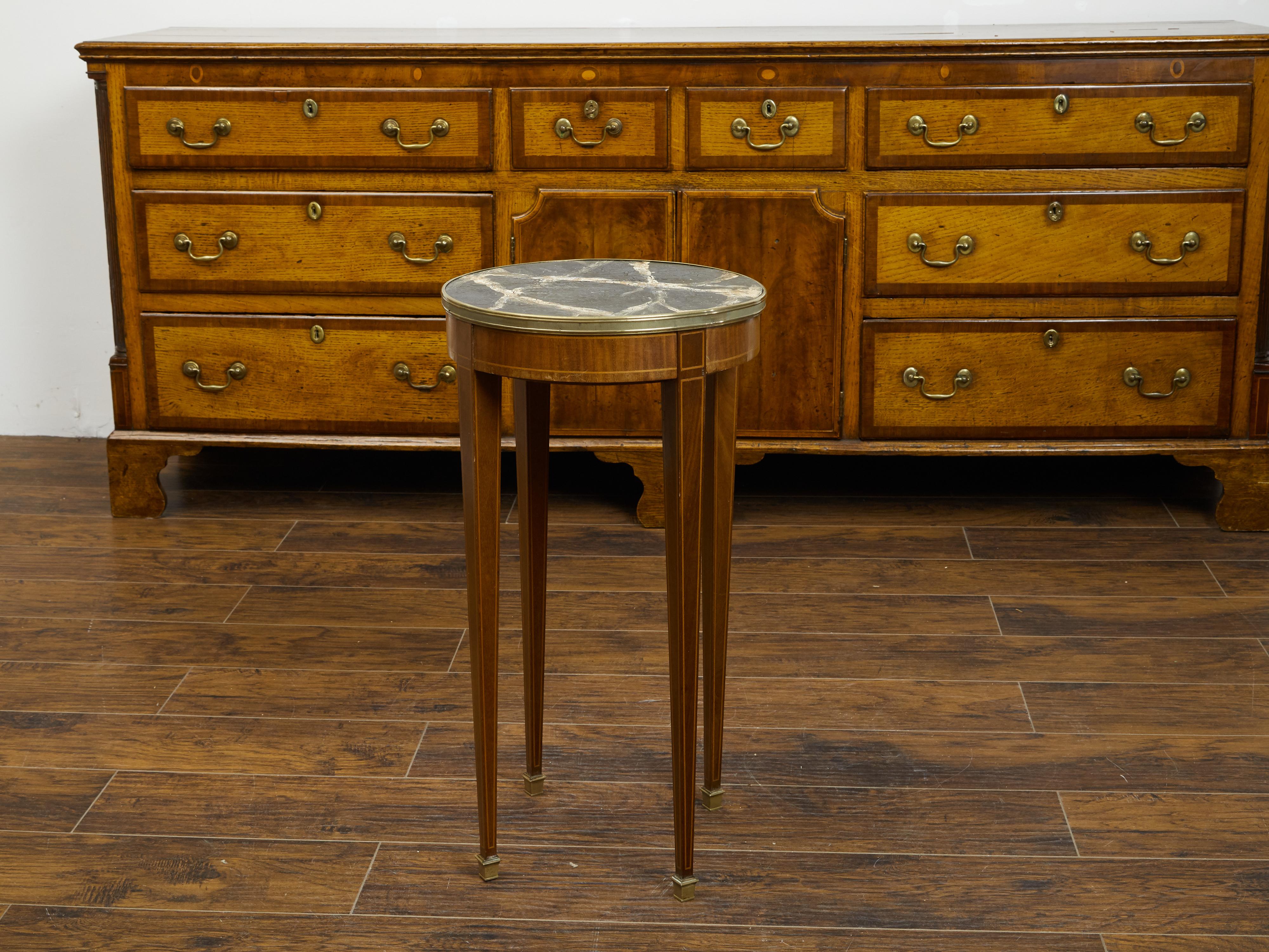 A French mahogany guéridon side table from the late 19th century, with faux painted marble top, banding and brass feet. Created in France during the last quarter of the 19th century, this mahogany guéridon features a circular top with faux marble