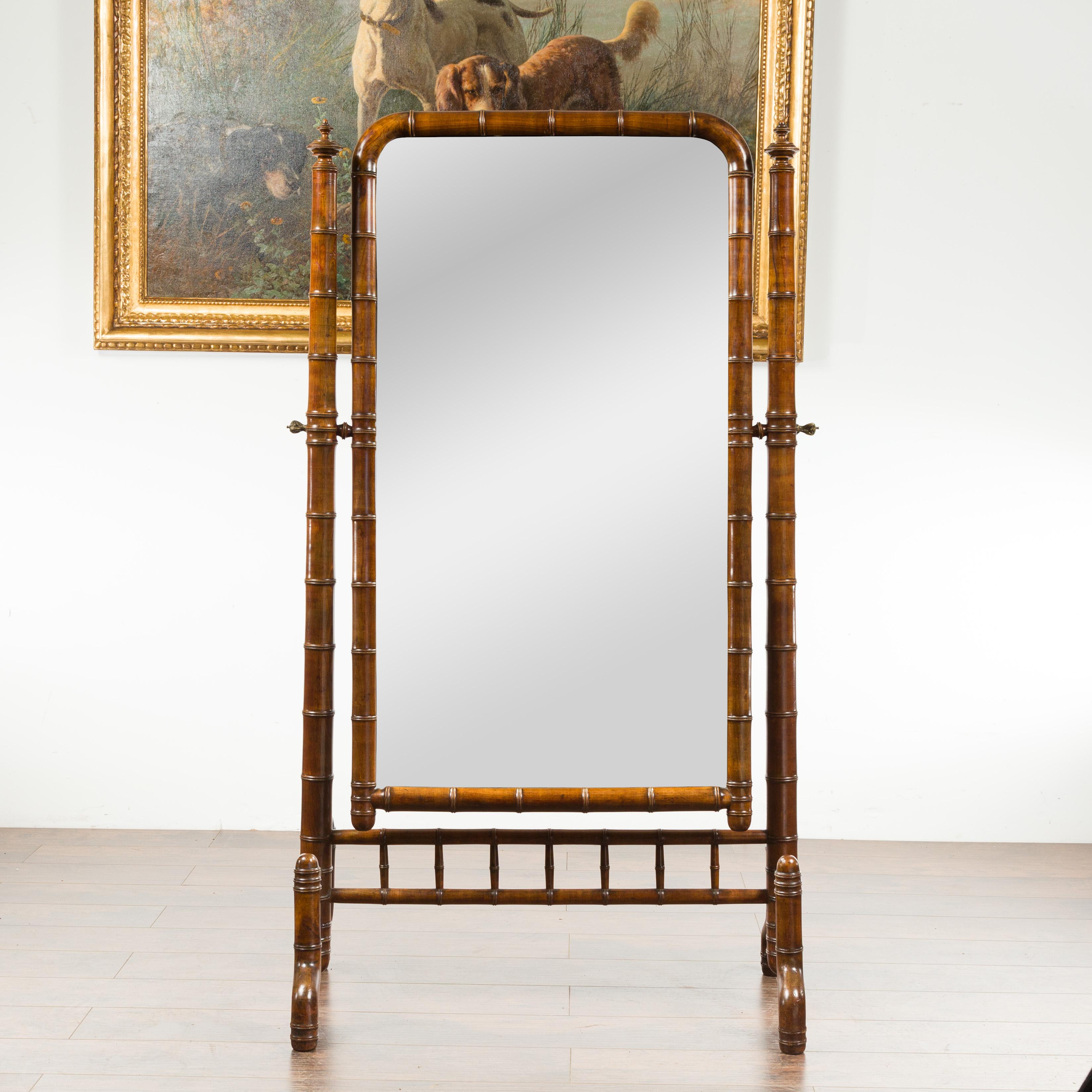 A French Napoléon III faux bamboo walnut cheval mirror from the late 19th century, with turned finials. Created in France a decade after the end of Emperor Napoléon III's reign, this walnut cheval mirror features a faux bamboo frame surrounding a