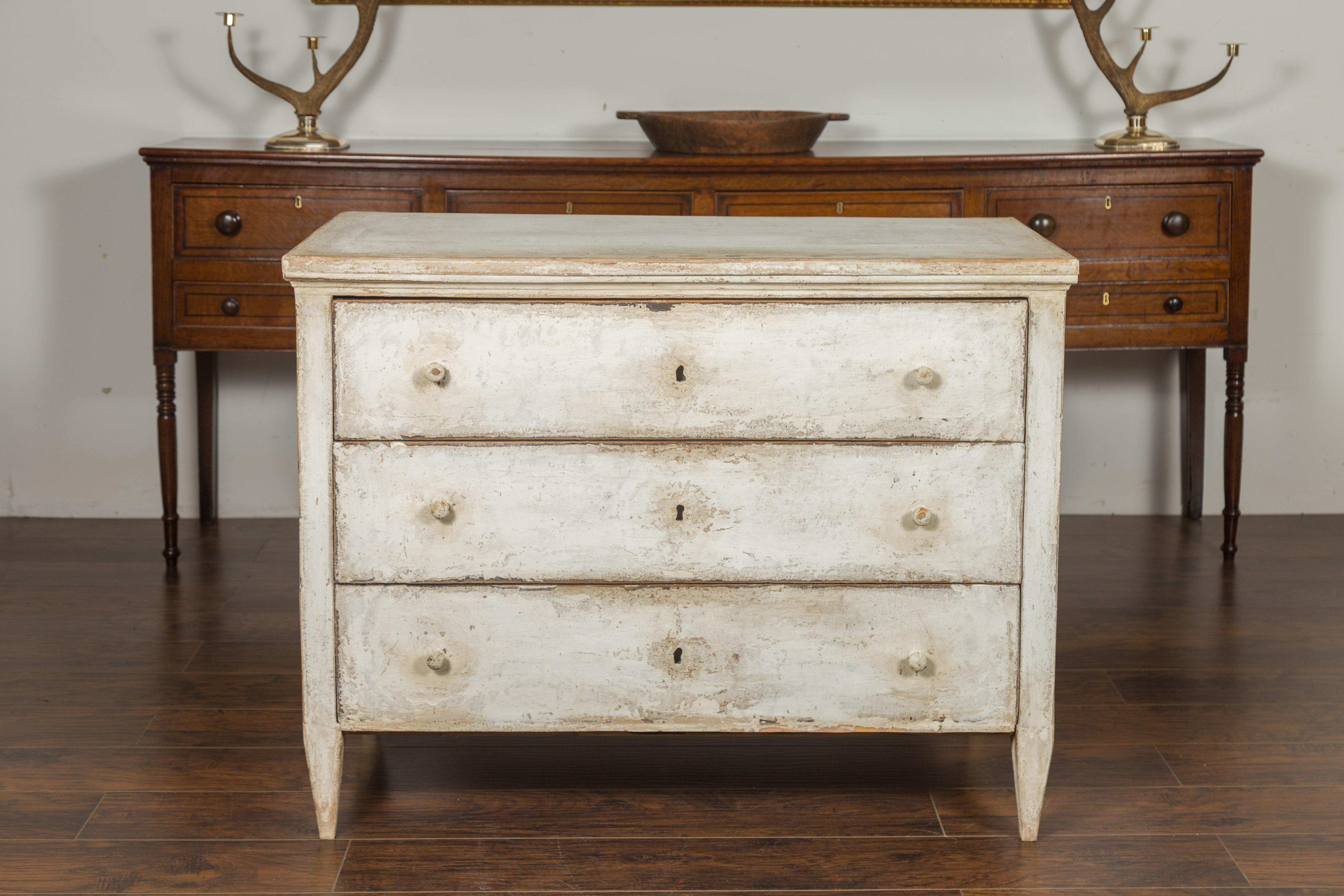 A French painted wood three-drawer chest with tapered feet and distressed patina. Created in France during the last quarter of the 19th century, this chest charms us with its simple lines and weathered finish. A rectangular top sits above three