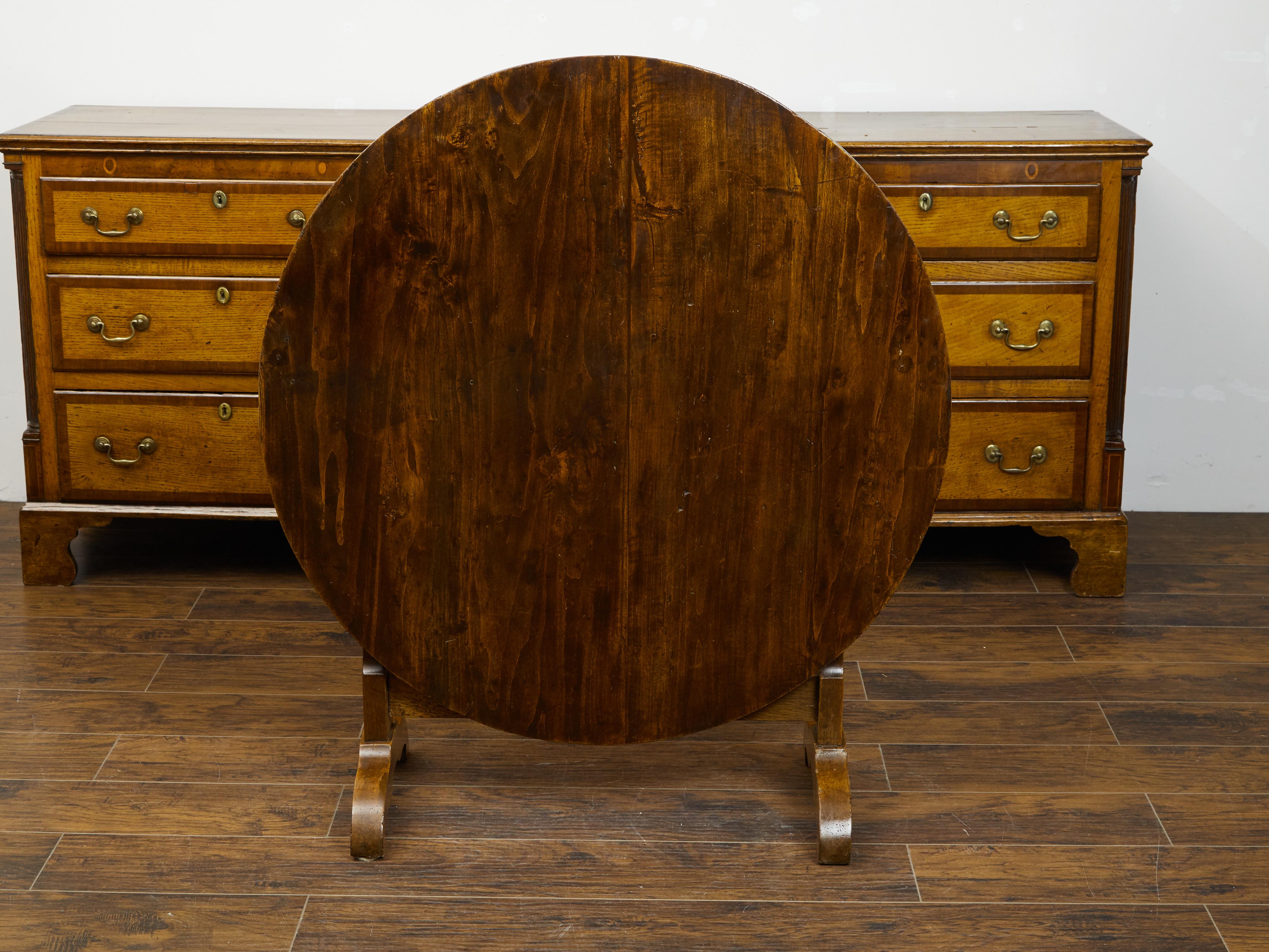 A French pine wine tasting table from the late 19th century, with circular top, trestle base and butterfly wedge. Created in France during the last quarter of the 19th century, this rustic wine tasting table features a round tilt-top supported by a