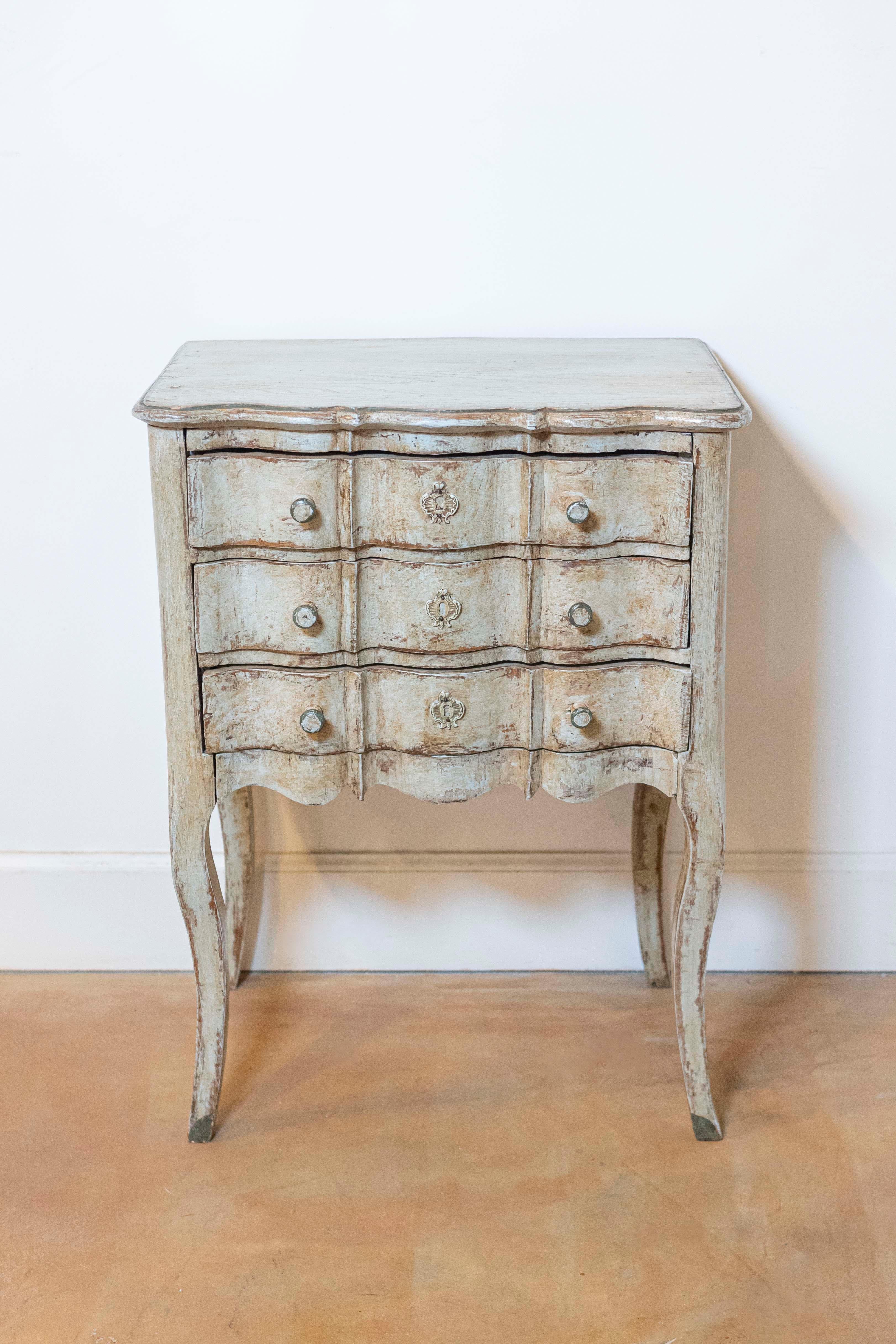 Comodino dipinto in stile French Rococo della fine del XIX secolo, con fronte a serpentina e tre cassetti. Creata in Francia nell'ultimo quarto del XIX secolo, questa cassettiera dipinta presenta un piano rettangolare con fronte a serpentina, posto