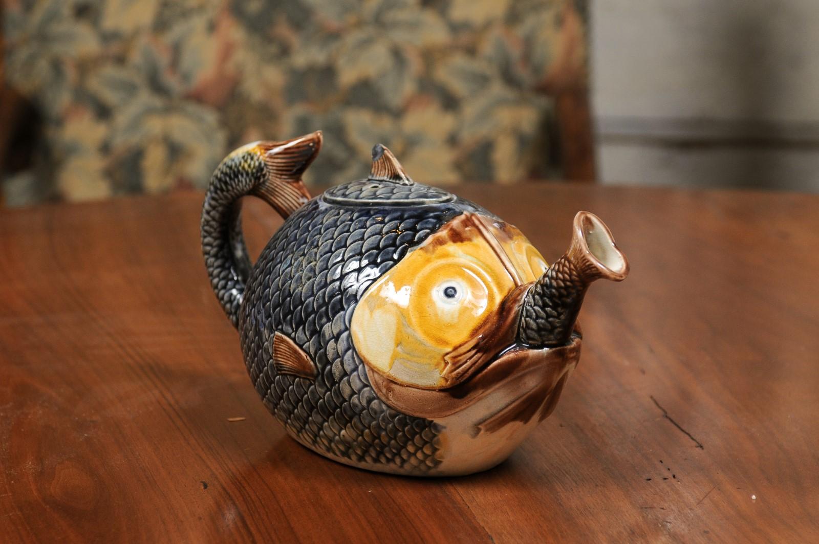 A French majolica teapot from the late 19th century depicting a fish eating another fish, with lid. Created in France during the last quarter of the 19th century, this majolica teapot attracts our attention with its unusual depiction of a fish