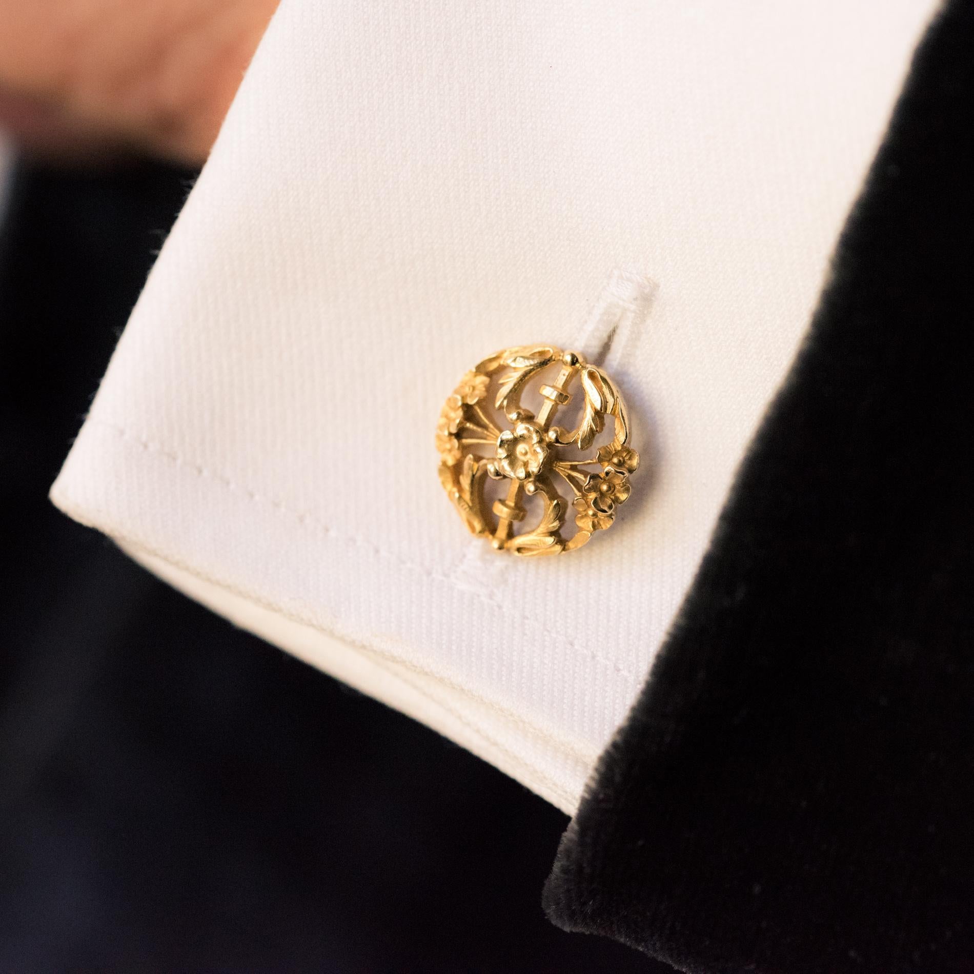 Pair of cufflinks in 18 carats yellow gold, eagle's head hallmark.
Round in shape, these antique cufflinks are pierced with flowers and foliage. They are connected by a curved rod, to a shuttle of the same decor, swiveling to attach to the