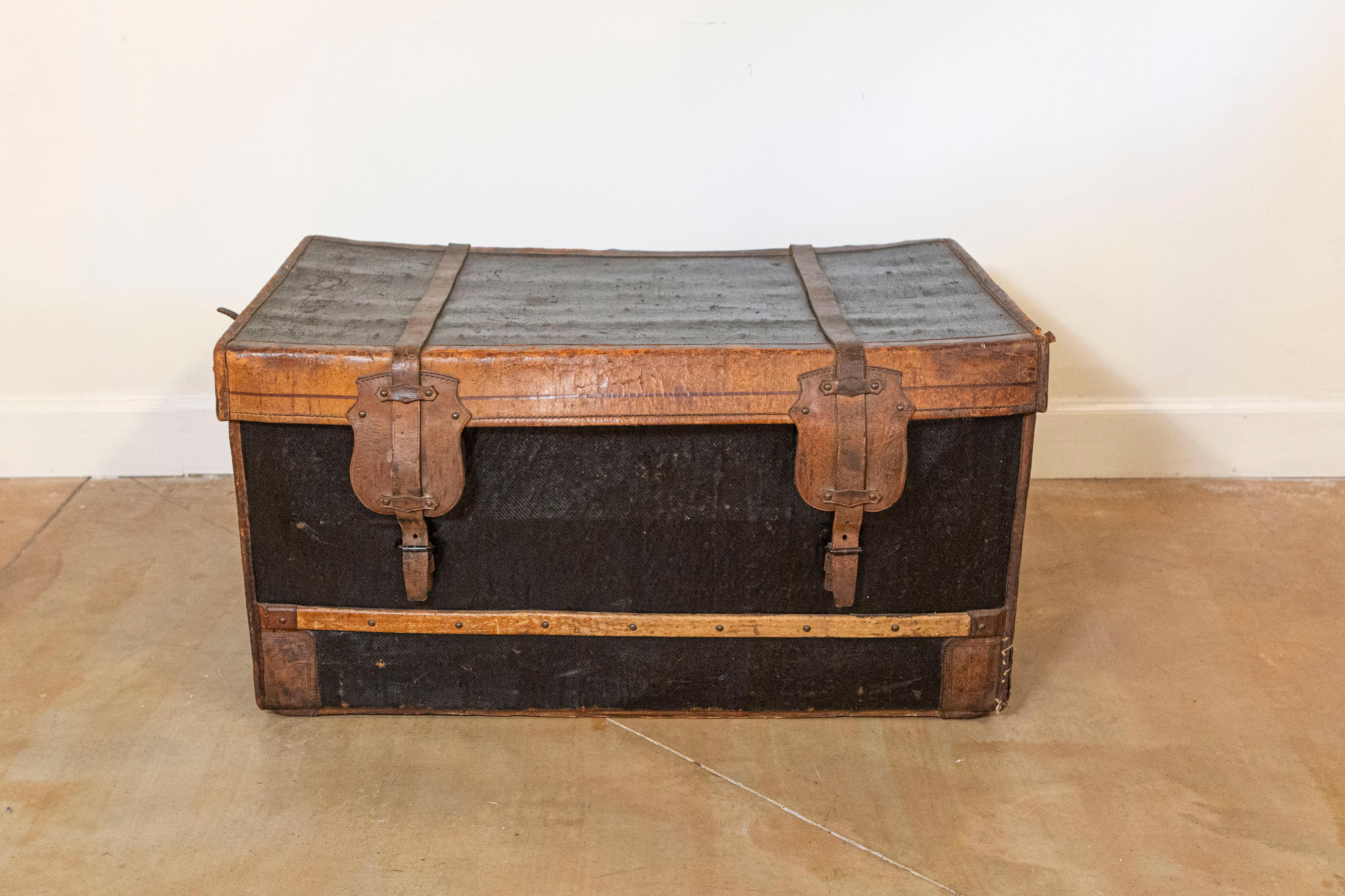 A French rustic travel trunk from the late 19th century, with nicely weathered patina. Created in France during the last decade of the 19th century, this trunk features a black and brown rectangular top opening thanks to leather straps to a small