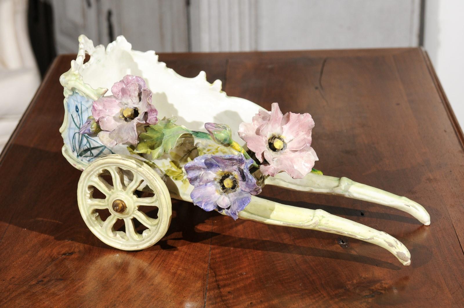 A French Majolica decorative wagon from the late 19th century, with barbotine décor of applied flowers. Born in France during the Belle-Époque era, this charming decorative object depicts a wagon (a charette in French), raised on two large wheels.