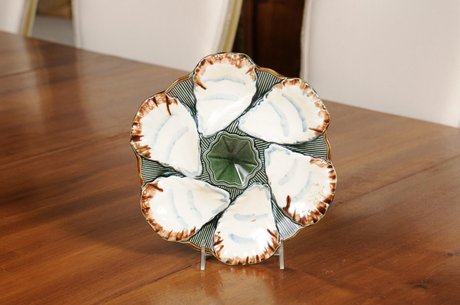 A French glazed Majolica Longchamp Terre de Fer oyster plate from the late 19th century, with central flower. We have two available, priced and sold $295 each. Created in France during the last decade of the 19th century, this oyster plate features