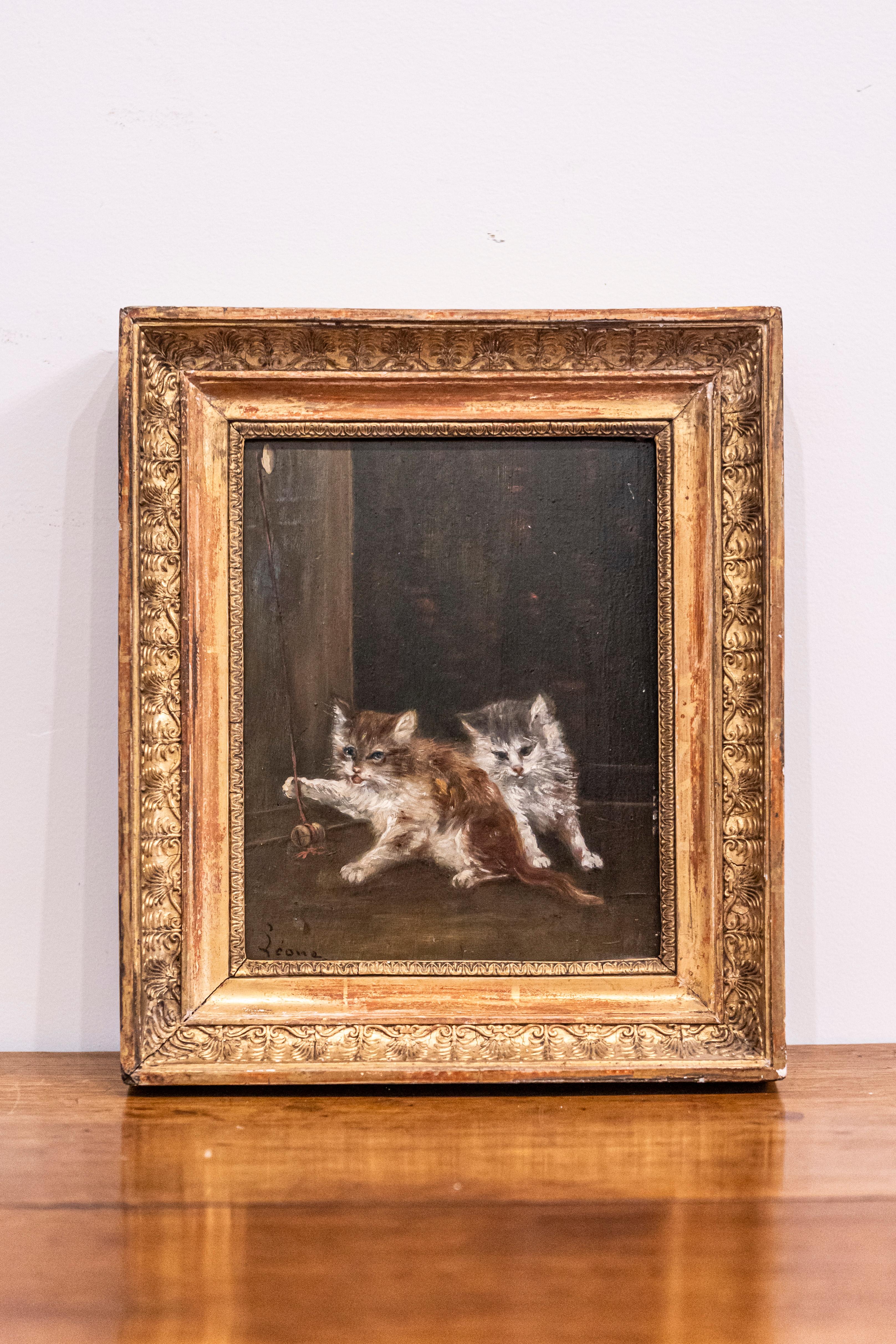 A French oil on canvas animal painting signed Laroche from the late 19th century with giltwood frame. This French oil on canvas painting features two lovely kittens playing with a stringed cork. Placed on a dark background that brings up the color