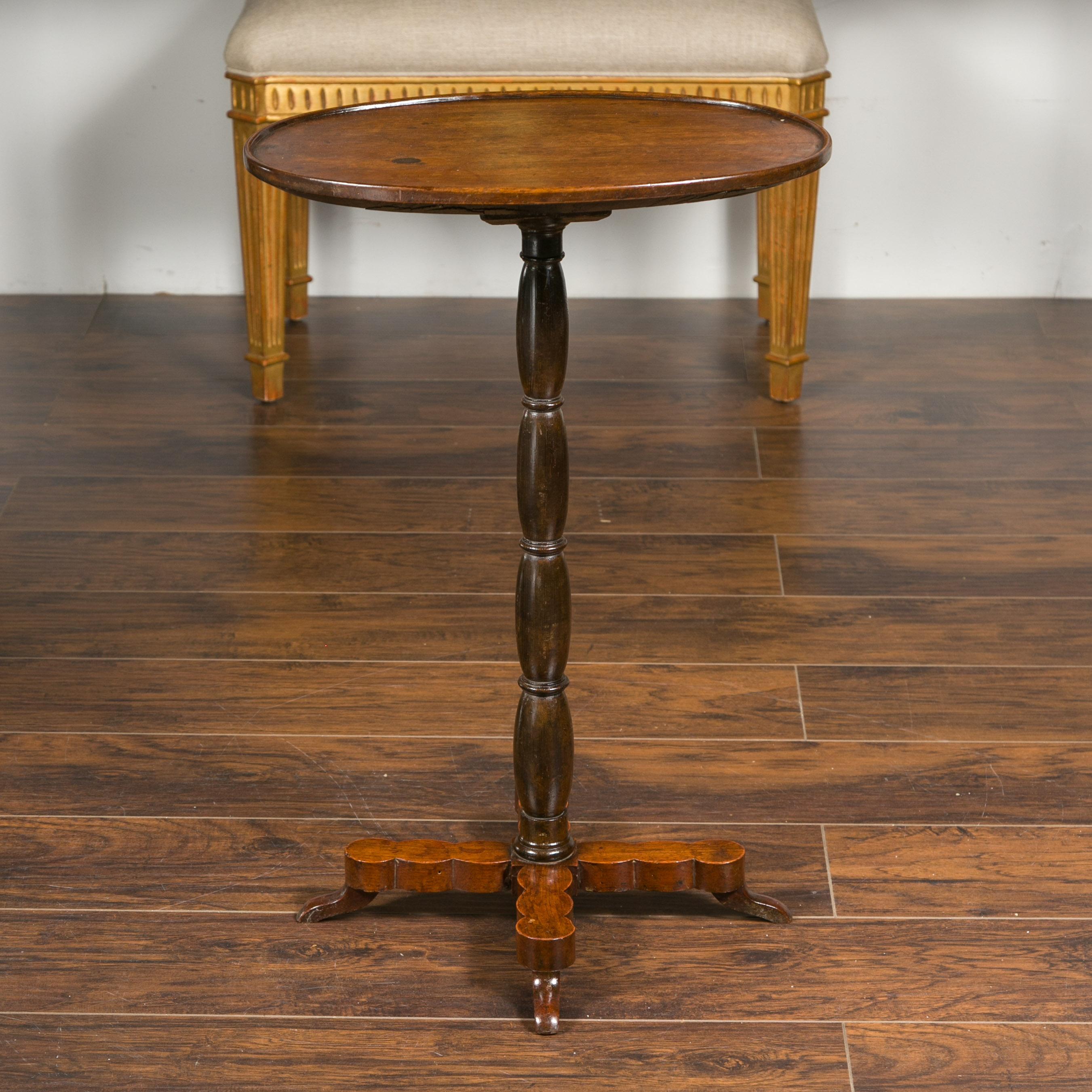 A French walnut guéridon table from the late 19th century, with oval top and turned pedestal base. Crafted in France during the last quarter of the 19th century, this walnut side table features an oval top with slightly raised edges, sitting above a