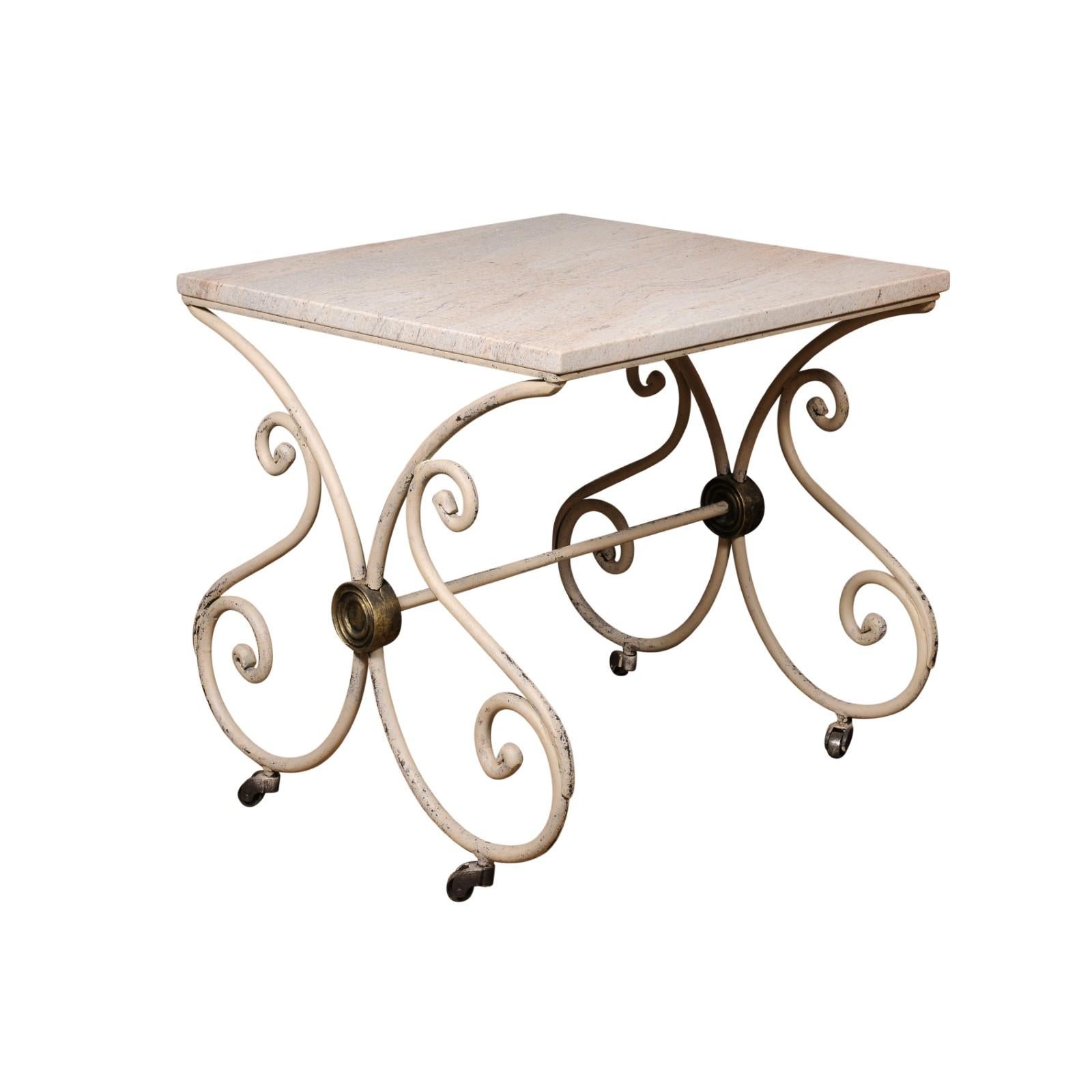 An antique French patisserie table from the late 19th century with recently added stone top and painted iron scrolling base on casters. Created in France during the last quarter of the 19th century at a time when the Impressionists when roaming the