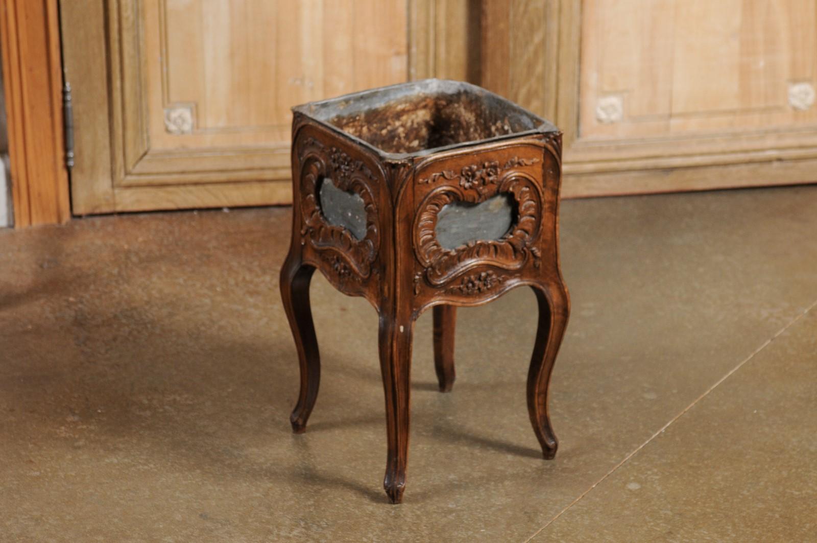 A French Rococo Revival period walnut planter from the late 19th century, with carved Rocailles motifs and tin liner. Created in France during the last quarter of the 19th century, this walnut planter features a square shaped body, carved with