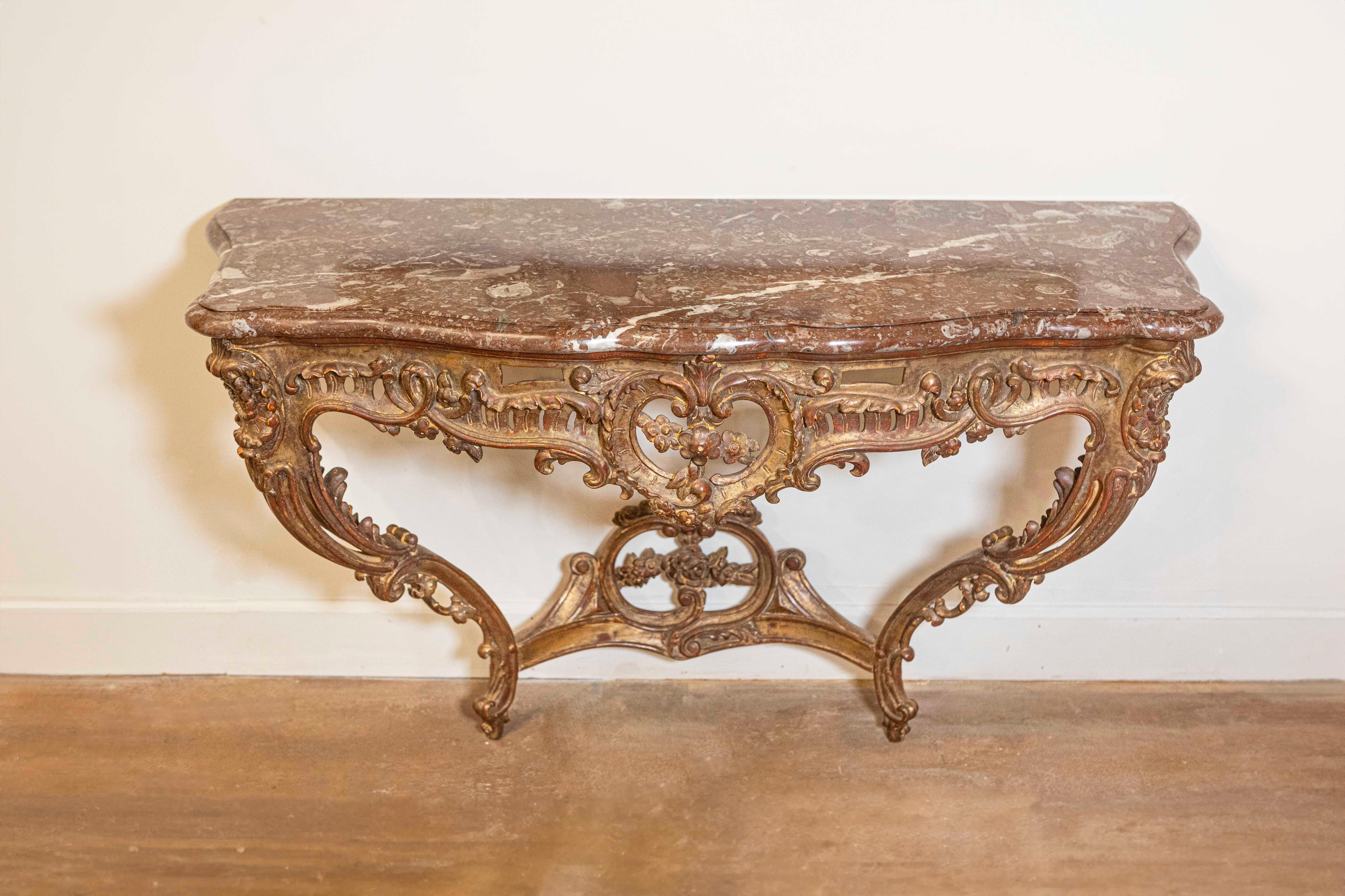 Console en bois doré sculpté de style rococo français de la fin du XIXe siècle, avec plateau en marbre rouge. Née en France au cours de la dernière décennie du XIXe siècle, cette table console présente un plateau en marbre rouge panaché à la