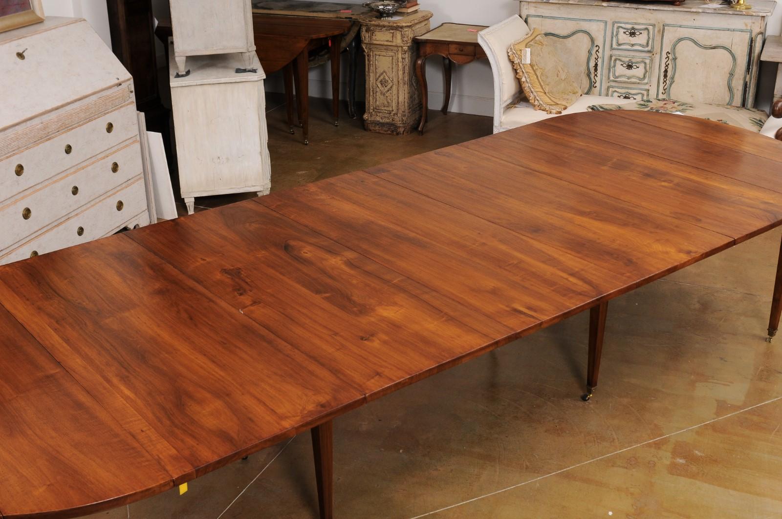 A French walnut oval shaped extension dining room table from the late 19th century, with five leaves, tapered legs and mounted on casters. Created in France during the last quarter of the 19th century, this French dining room table features a walnut