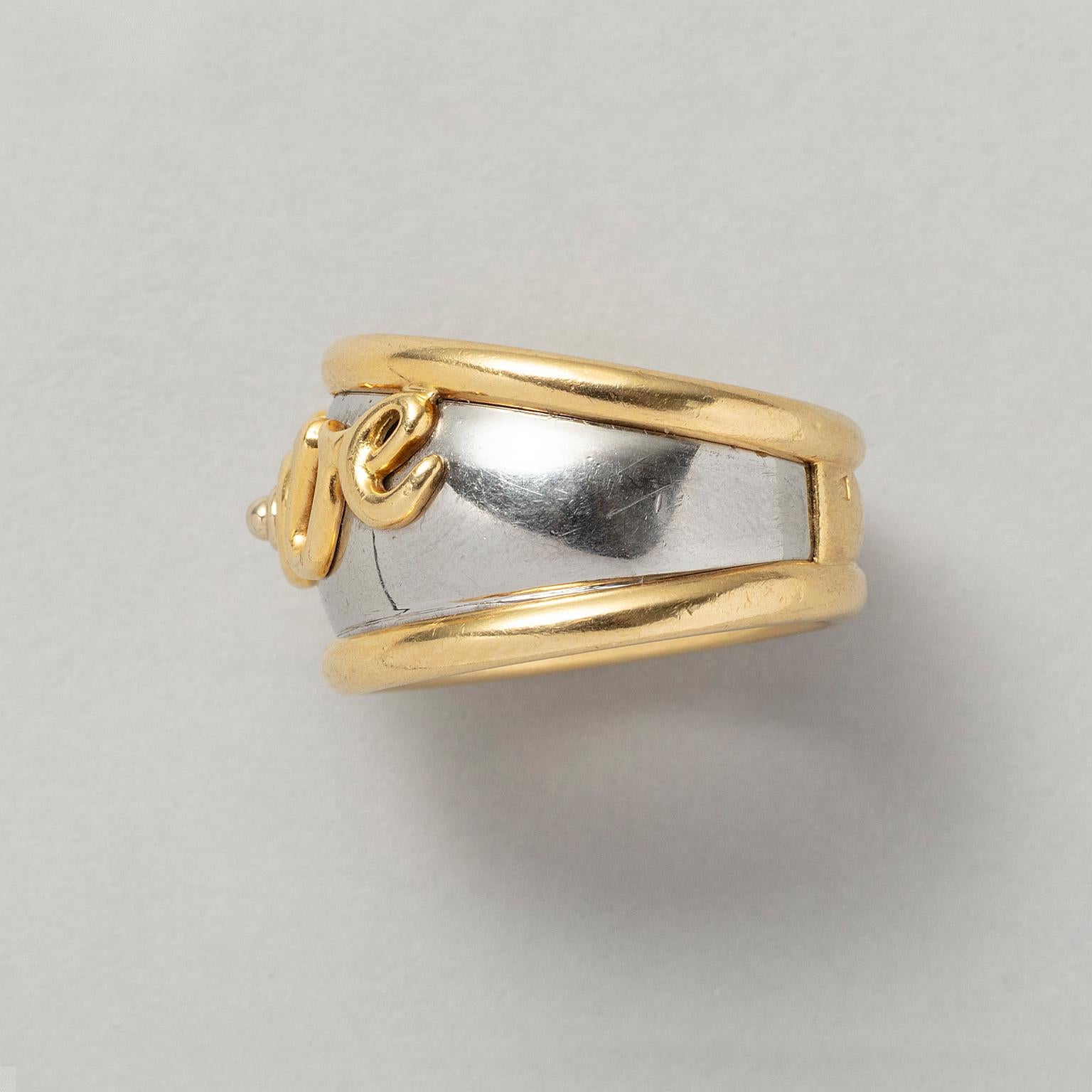 Anello a fascia in oro giallo 18 carati e acciaio con la parola LOVE in cusrive, firma indossata e marchio di fabbrica di Pery & Fils, Francia, circa 1980.

peso: 11,7 g
Misura dell'anello: 18,25 mm / 8 1/4 US