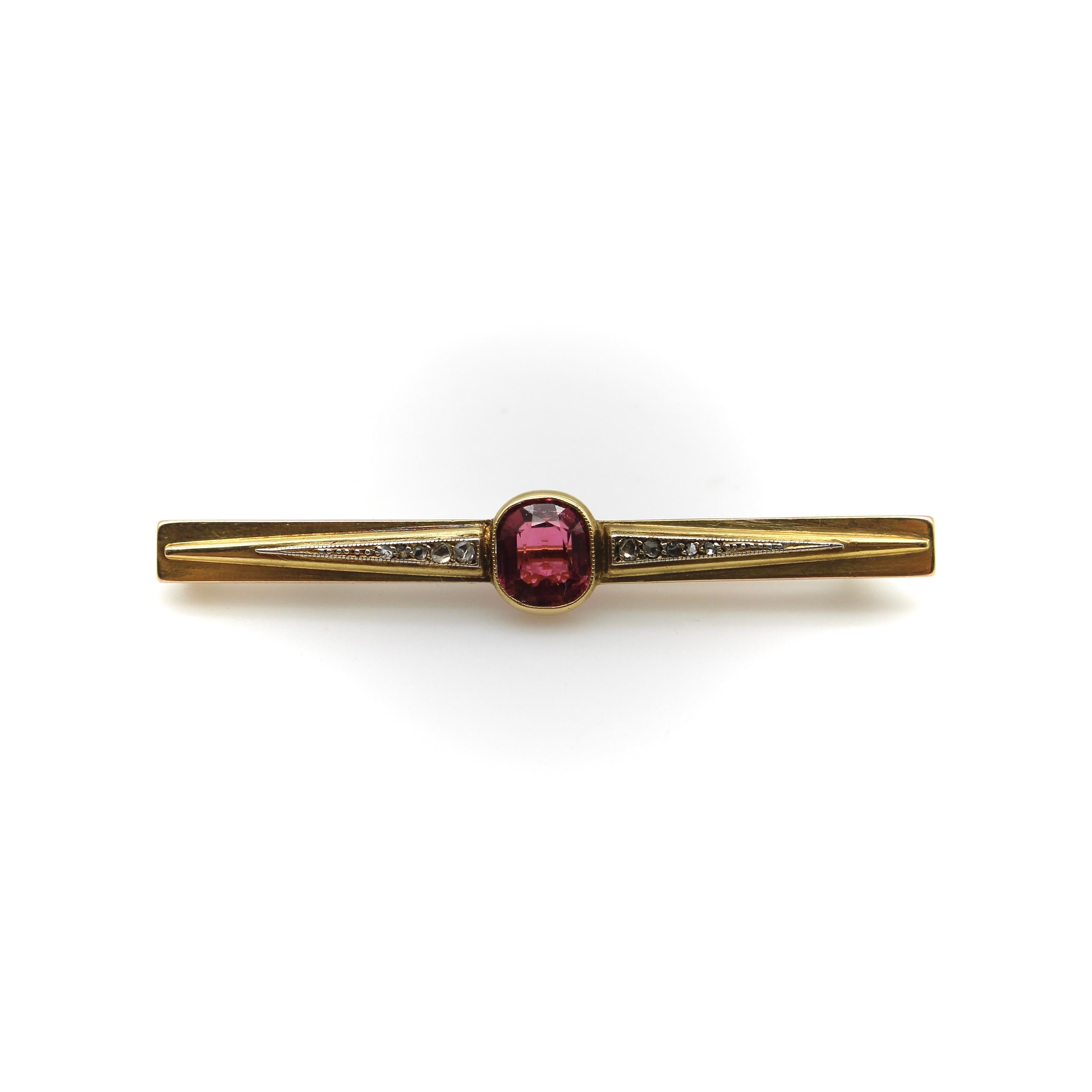 Circa 1870, this gorgeous French brooch features a pink tourmaline as its centerpiece, flanked by Rose Cut diamond studded triangles along a horizontal 18k gold pin. The tourmaline is oval-shaped and bezel set—it is a nice old cut stone with complex