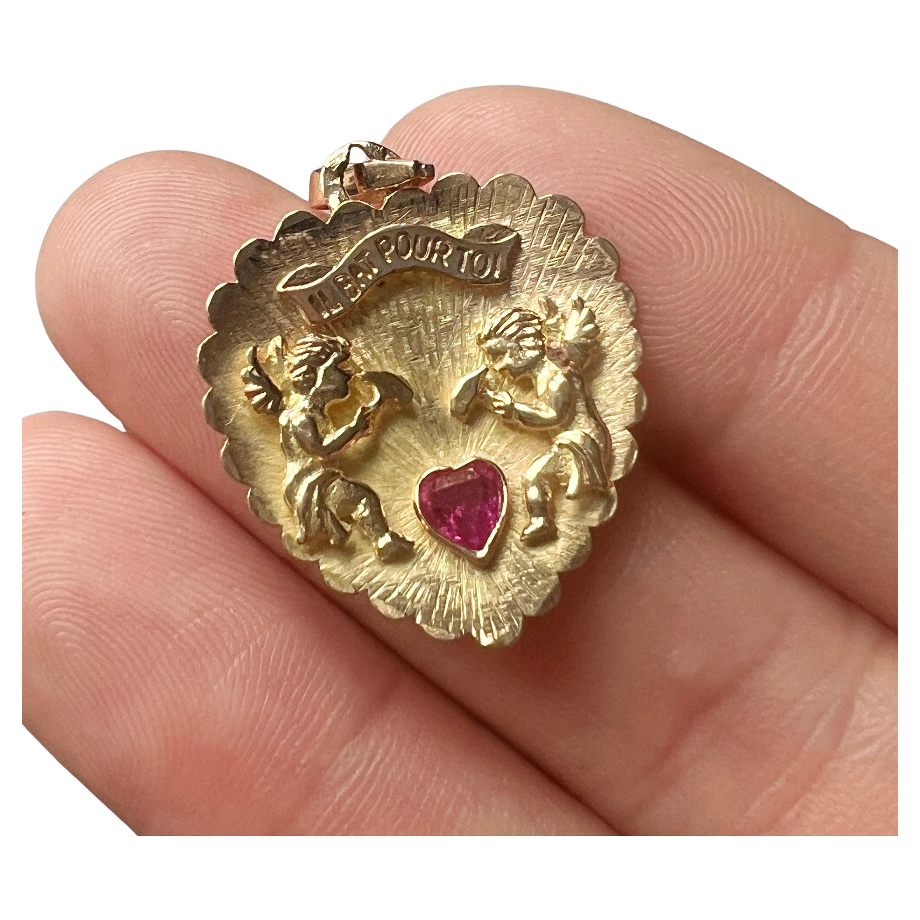 For sale a romantic 18K gold pendant, expressing love and devotion captured in a heart-shaped masterpiece. The pendant is a French work and it features two winged angels, each delicately wielding a hammer, symbolizing the gentle beating of a shared