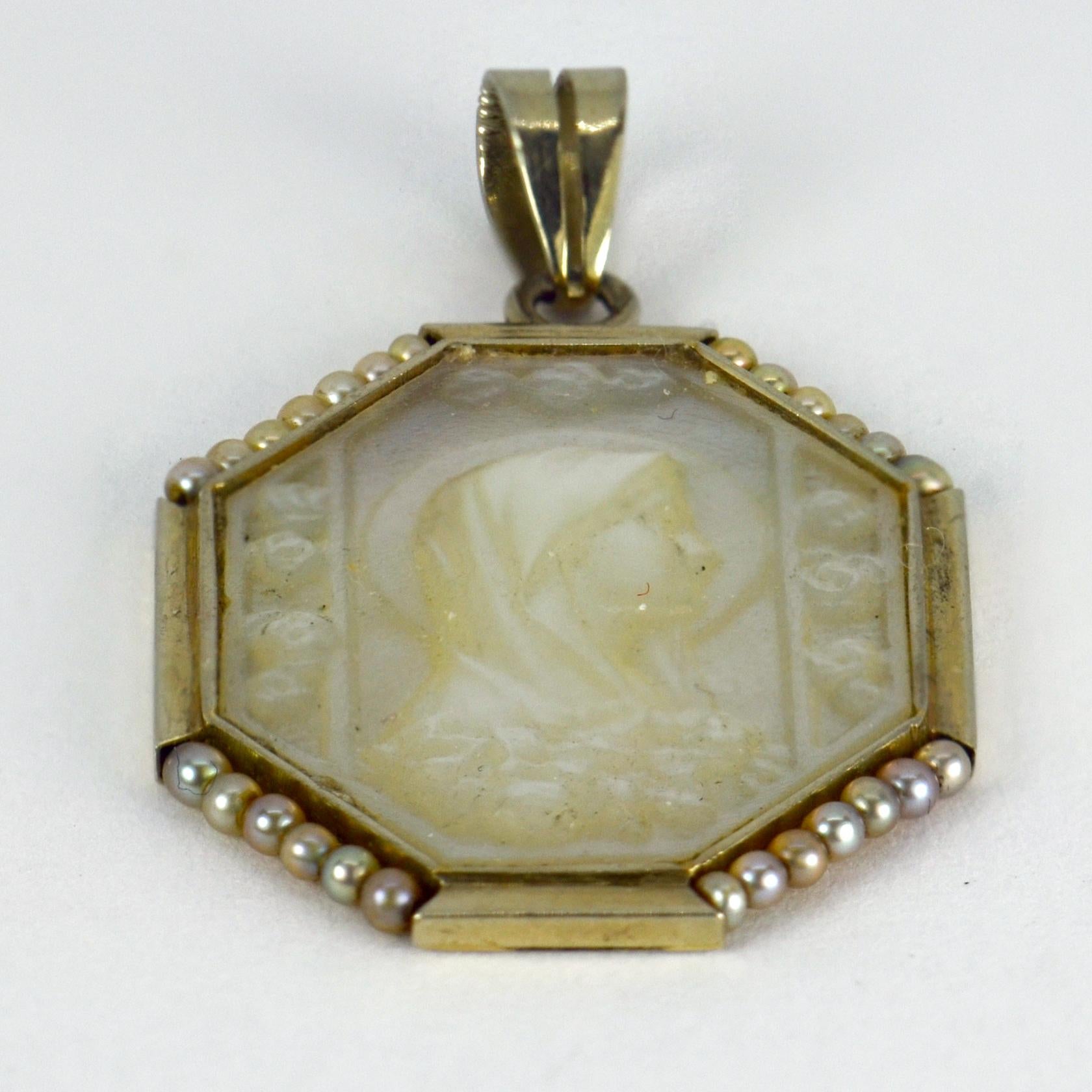 A French 18 karat (18K) white gold Art Deco pendant set with a large mother of pearl tablet engraved with a cameo of the Virgin Mary among flowers, surrounded by 24 natural grey seed pearls. Stamped with the French eagle’s head for 18 karat gold and